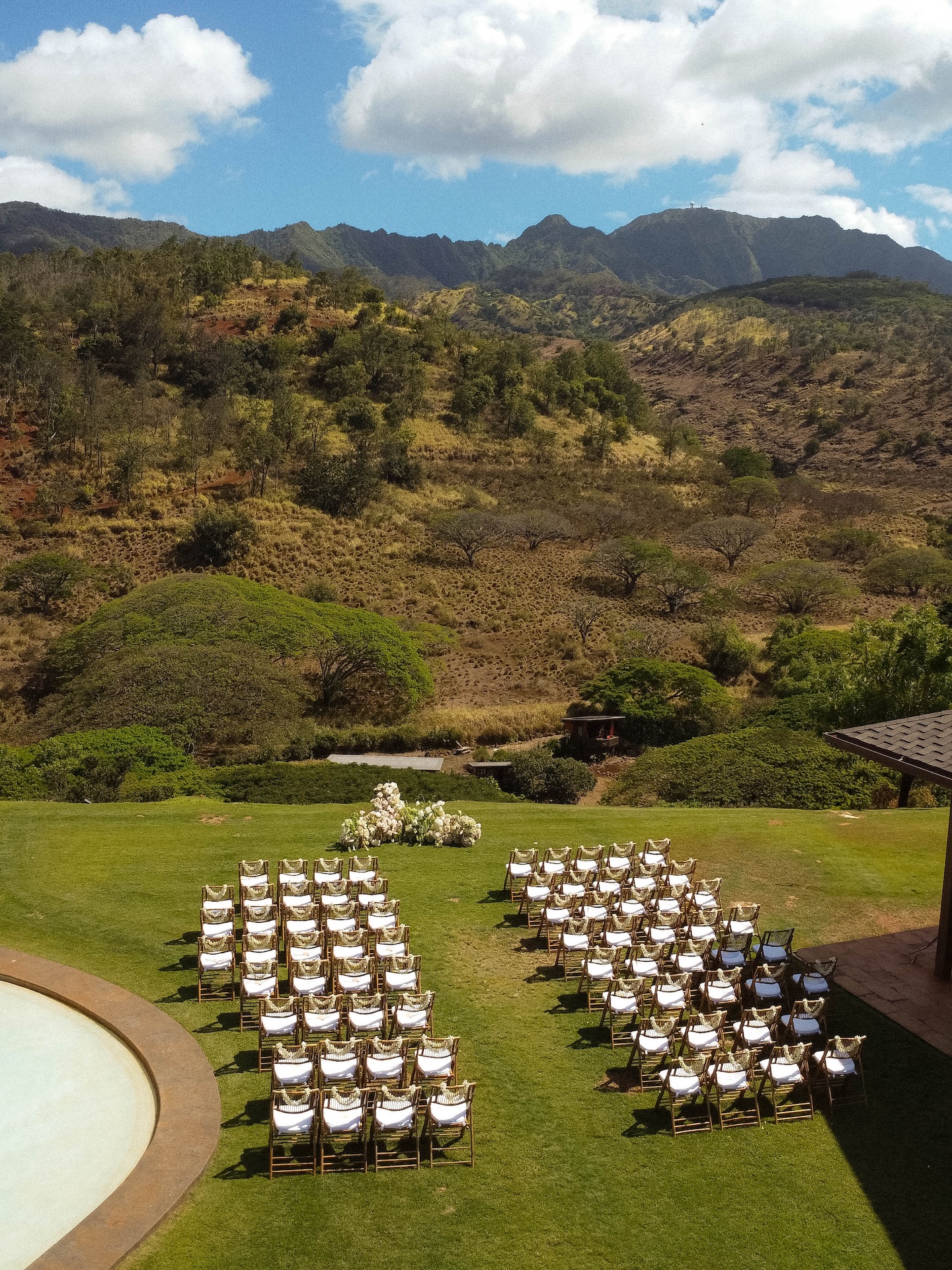 Ceremony setup at Kaʻala Vista with chairs arranged on the lawn and the North Shore mountains in the background for a Hawaii destination wedding.