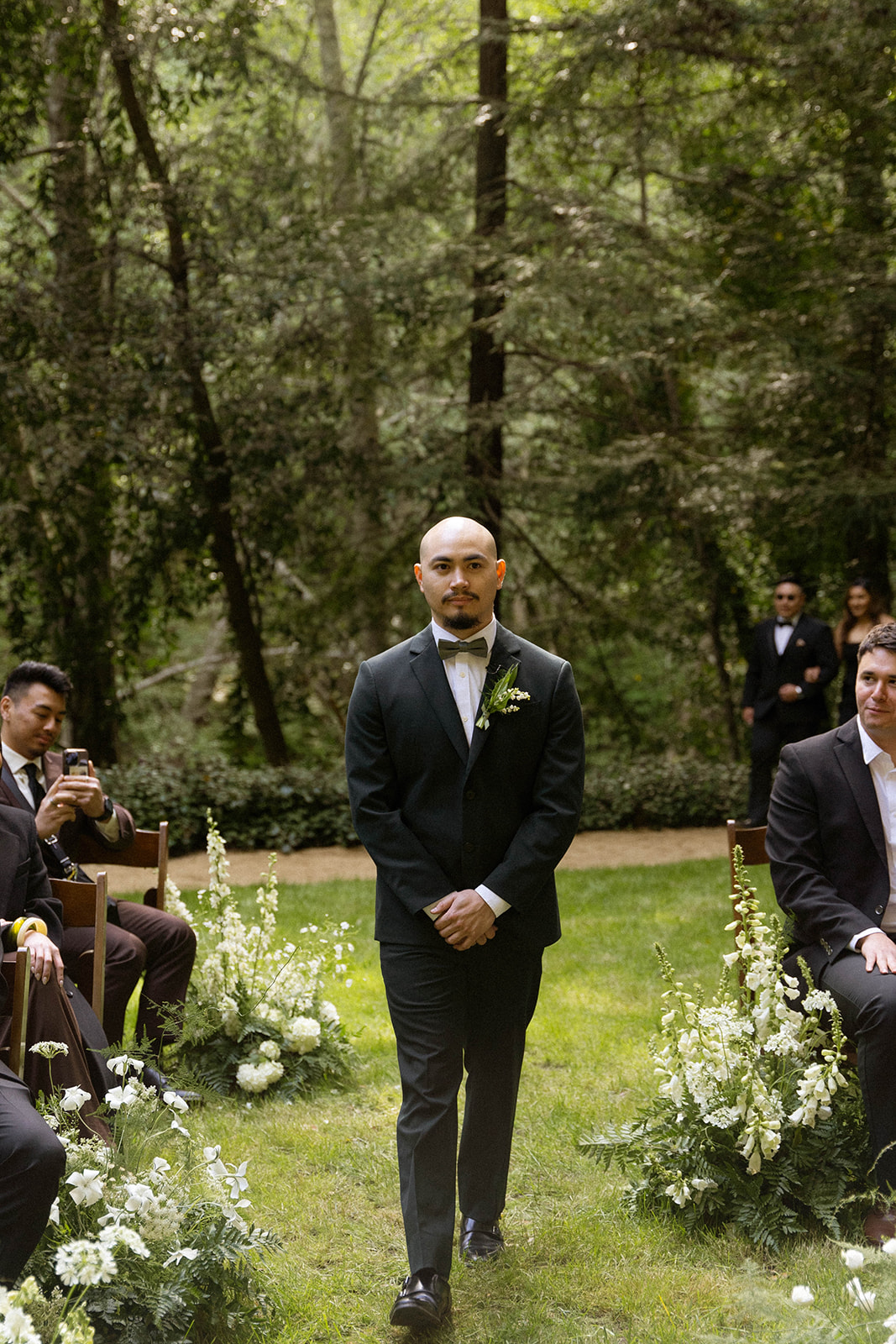 Groom walking down the aisle at a Big Sur wedding ceremony with guests watching.