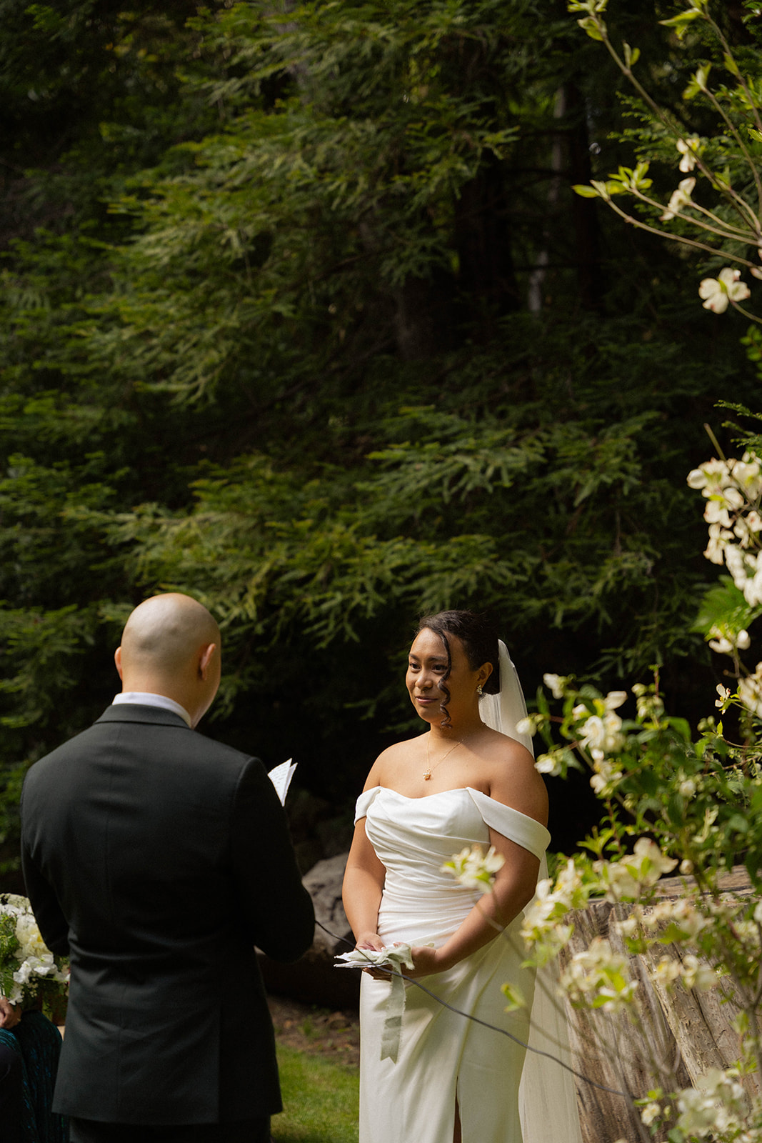 Bride smiling as she listens to vows during their intimate Big Sur wedding ceremony in the redwoods.