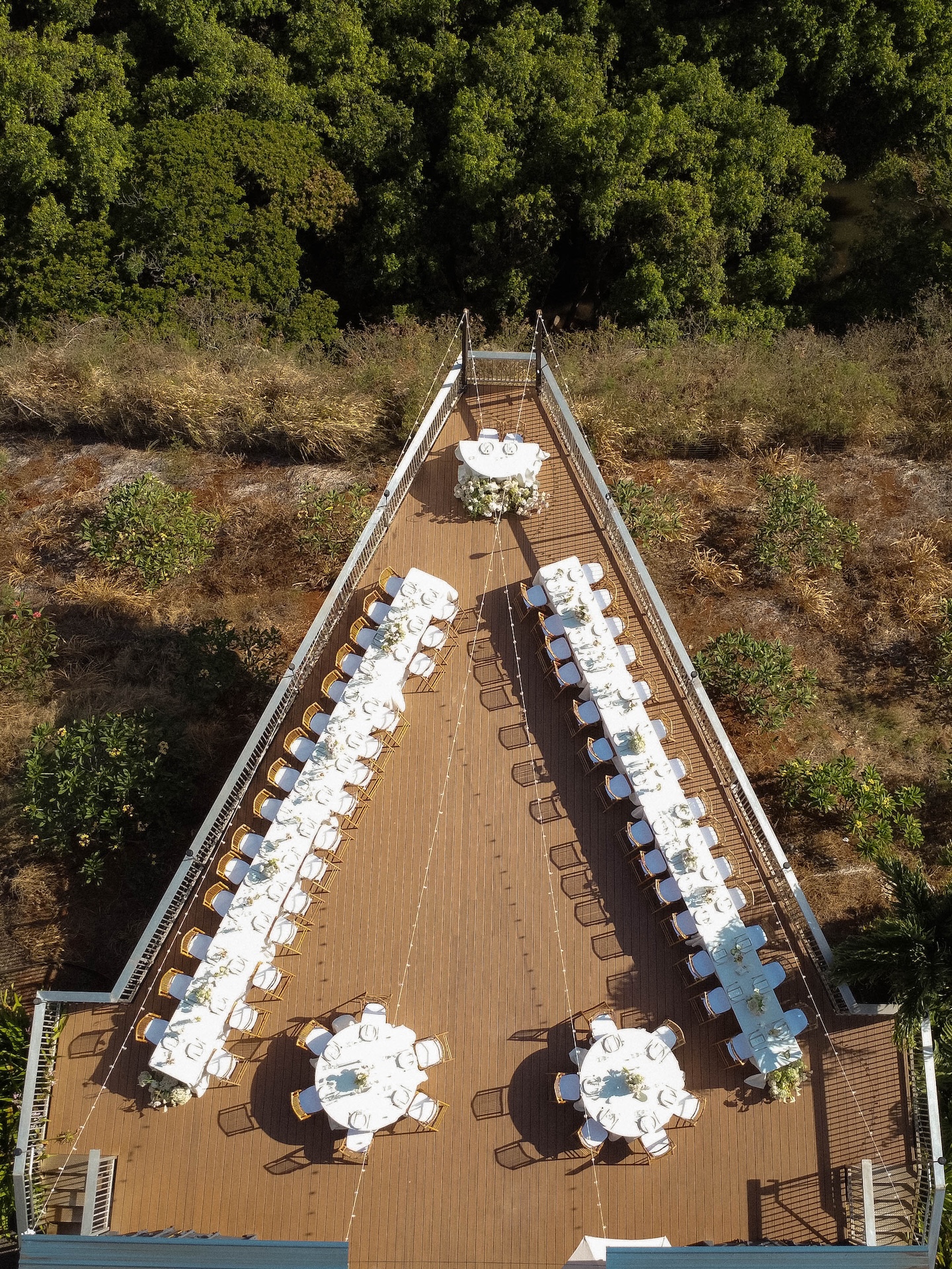 Aerial view of the Kaʻala Vista wedding reception deck with long tables and round tables set for guests.