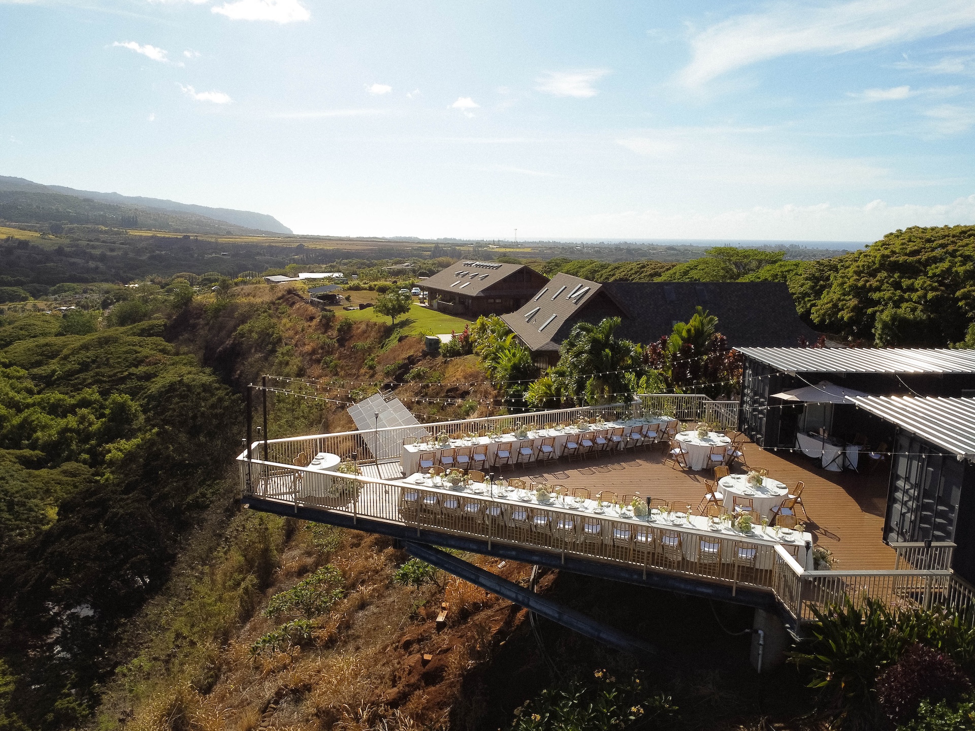 An overhead view of the reception deck set with round and long tables overlooking the valley.

