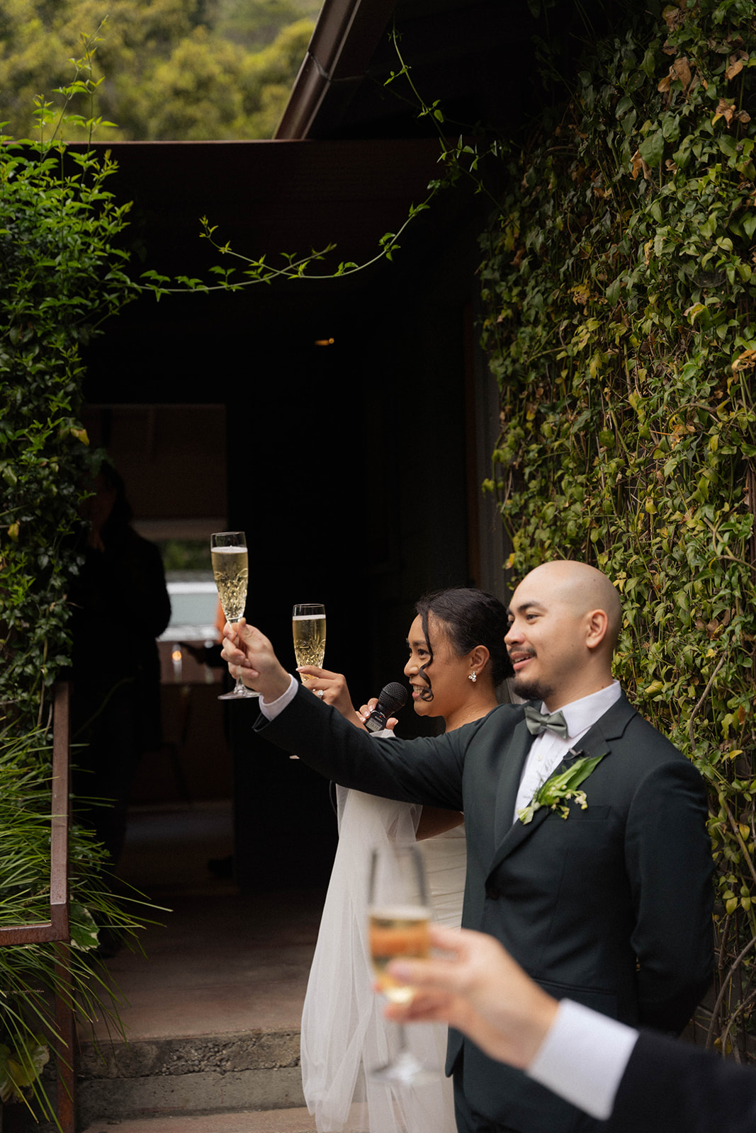Bride and groom raising champagne glasses for a toast at their Big Sur wedding reception at a beautiful forest venue.