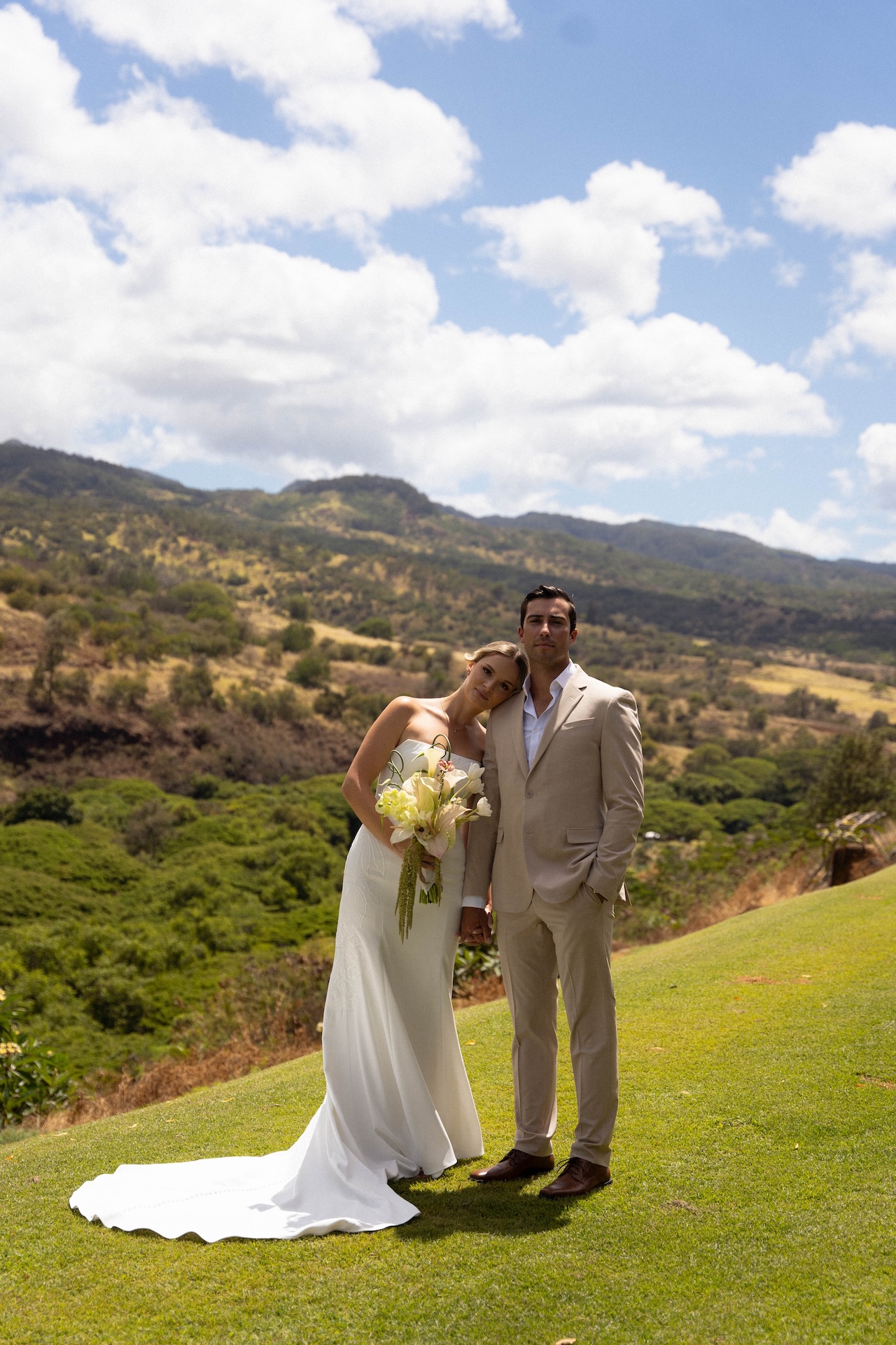 Couple posing together on a hill with mountain views behind them at their Hawaii destination wedding on Oʻahu.