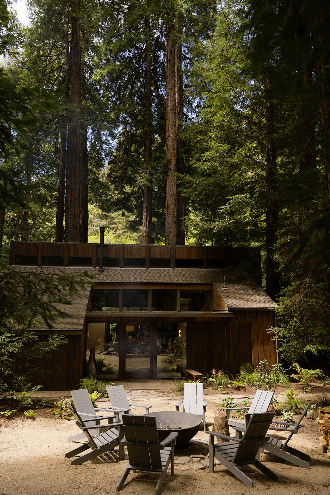 Cozy forest cabin with Adirondack chairs around a fire pit, a perfect Big Sur wedding weekend retreat.