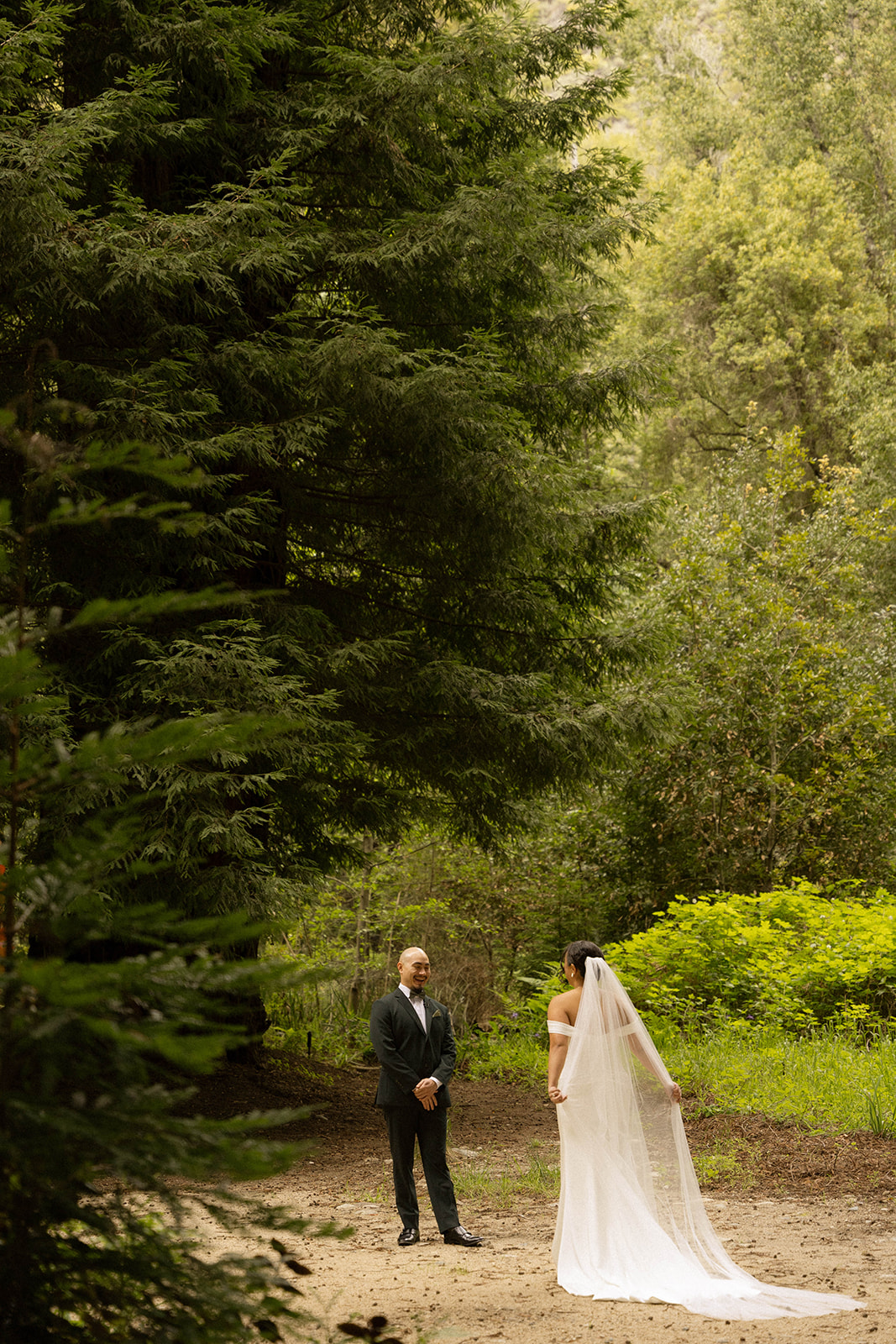 Bride and groom share a quiet moment during their first look surrounded by tall redwoods at their Big Sur wedding.