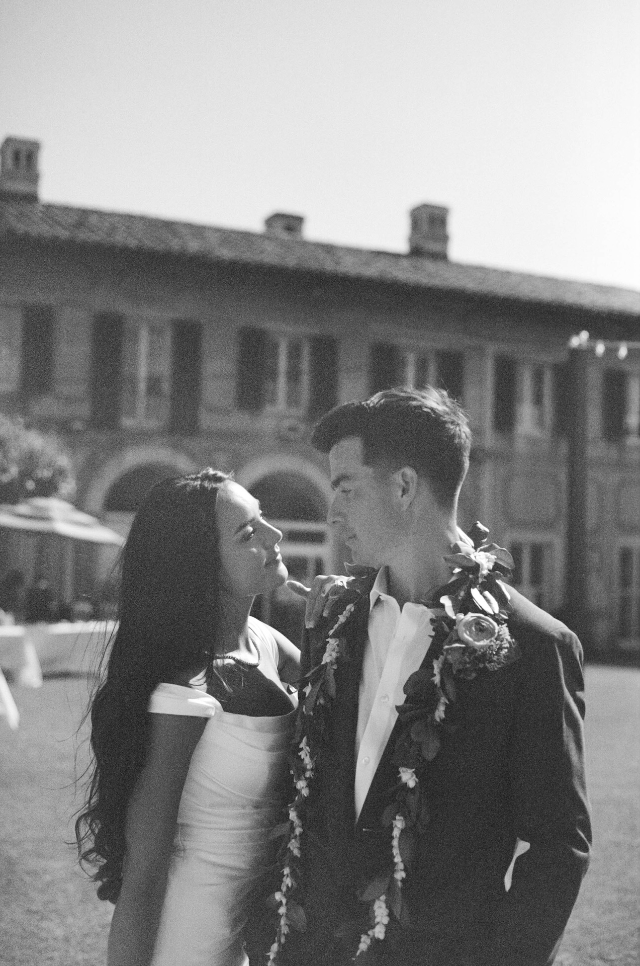 A black and white portrait of the bride and groom locking eyes in front of the villa, the bride gently touching the groom’s chest — captured by a destination wedding photographer.