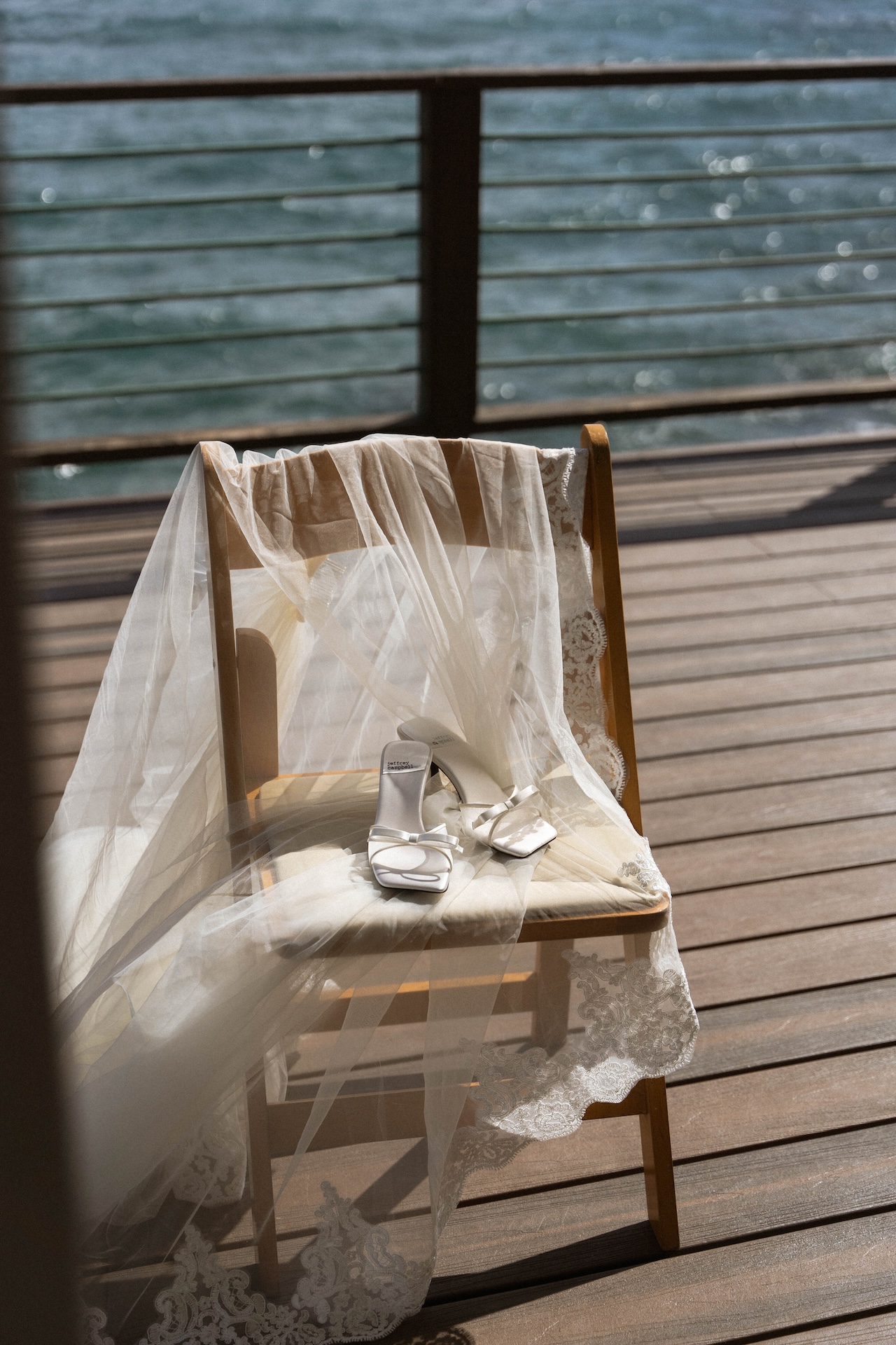 A soft lace veil and white bridal heels rest on a wooden chair, capturing elegant details from a tropical airbnb wedding morning.