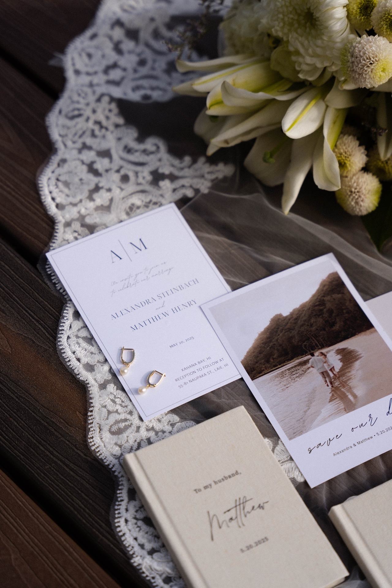 Flat lay of wedding details including invites, vow books, pearl earrings, and flowers — an elegant snapshot from their airbnb wedding day.