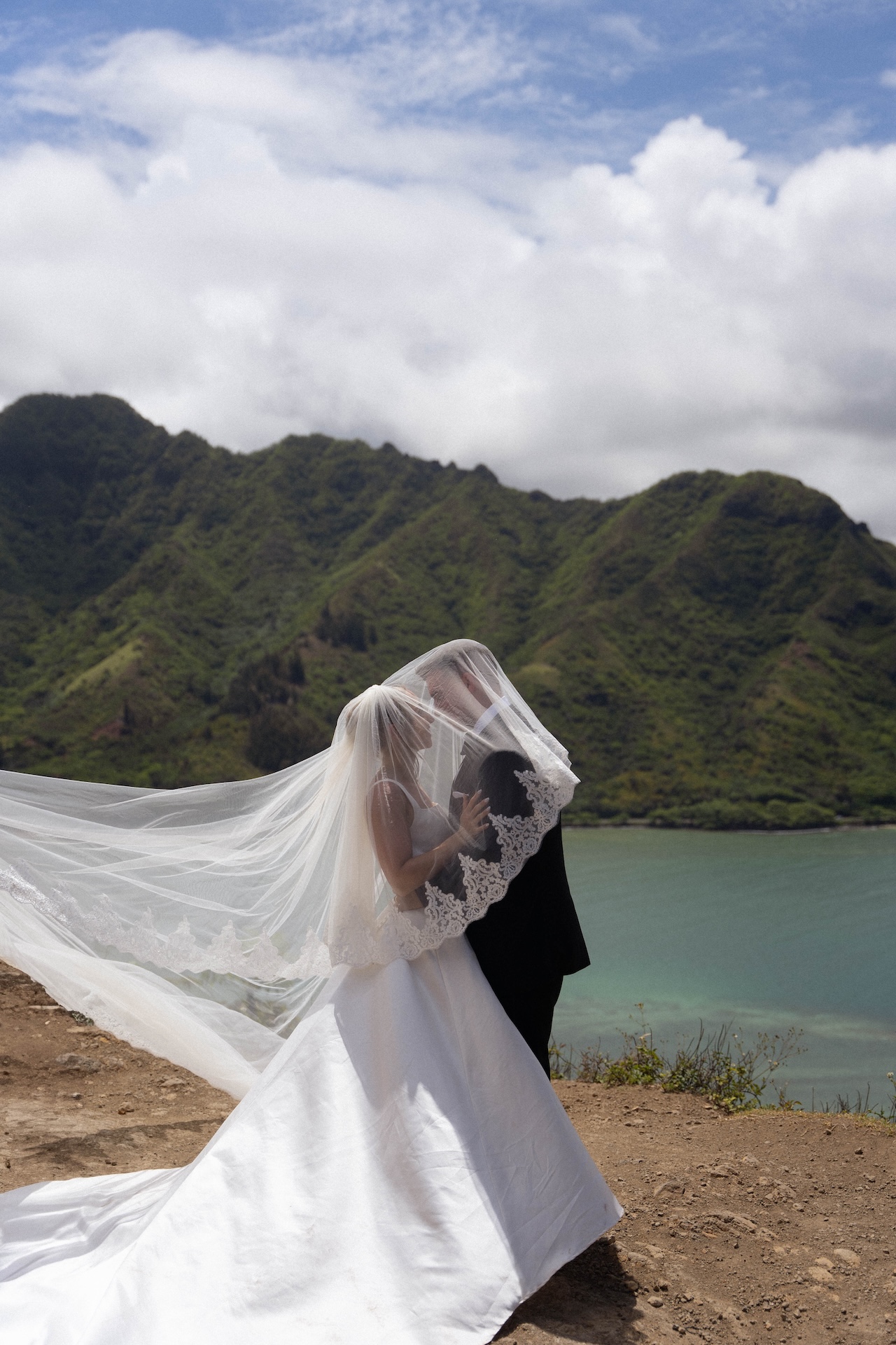 Close-up of bride and groom looking into each other’s eyes under the veil, sharing a tender, just-married moment from their heartfelt airbnb wedding celebration.