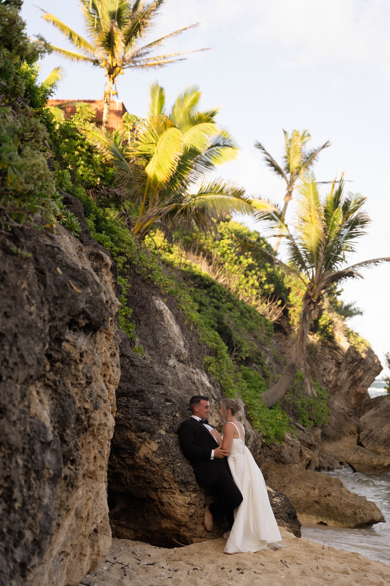 The bride leans in close to the groom on a sandy cove during golden hour, one of many serene airbnb wedding moments.