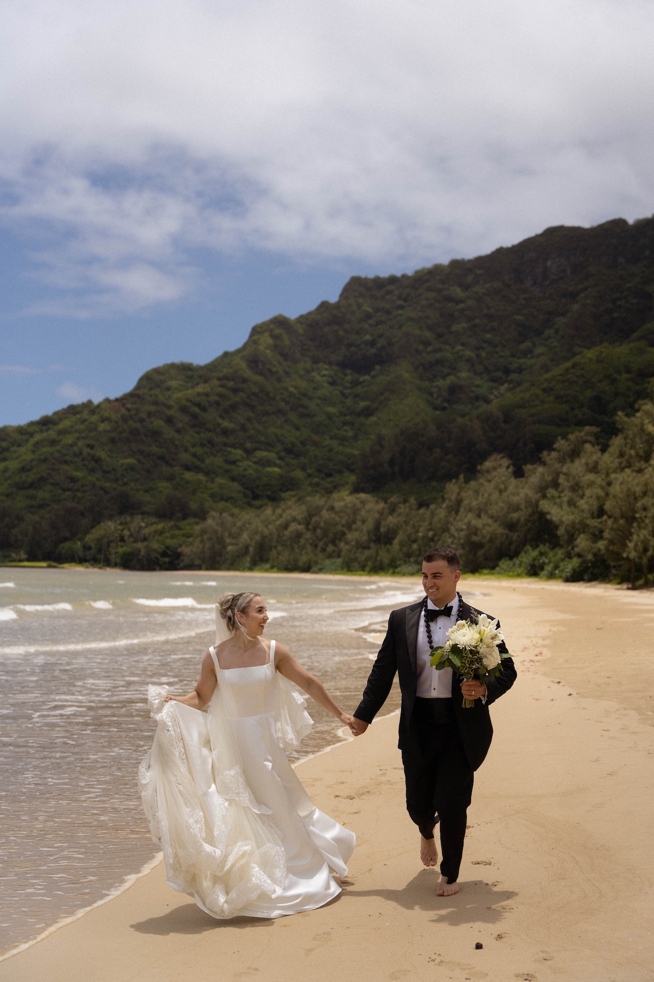 Bride and groom running together hand in hand on the beach after their Airbnb wedding ceremony.