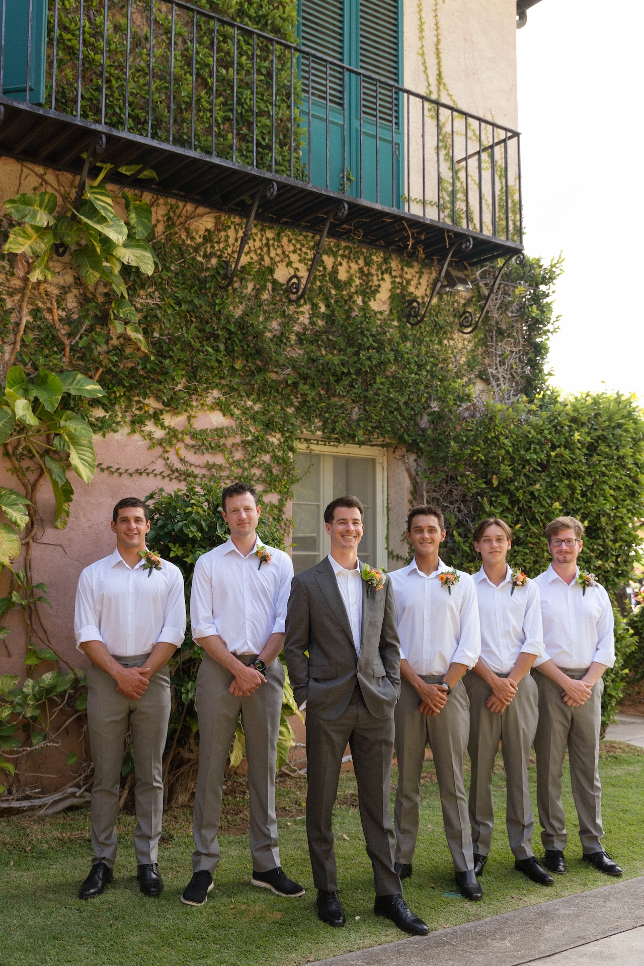 The groom stands proudly with his groomsmen in front of a vine-covered Mediterranean building — a classic group shot by a destination wedding photographer.