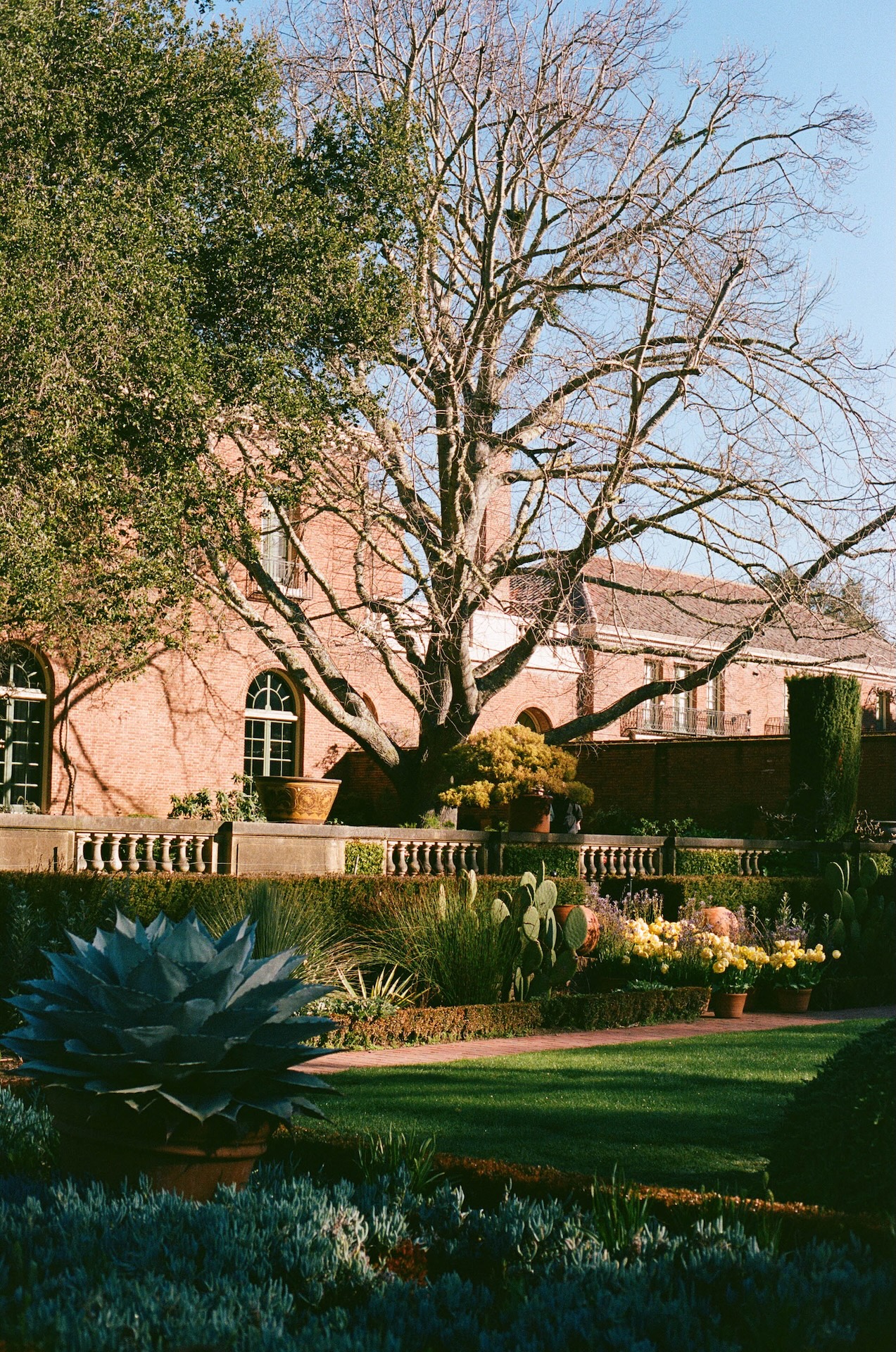 The exterior of a brick estate surrounded by manicured gardens and lush greenery at one of the most stunning wedding estate venues.
