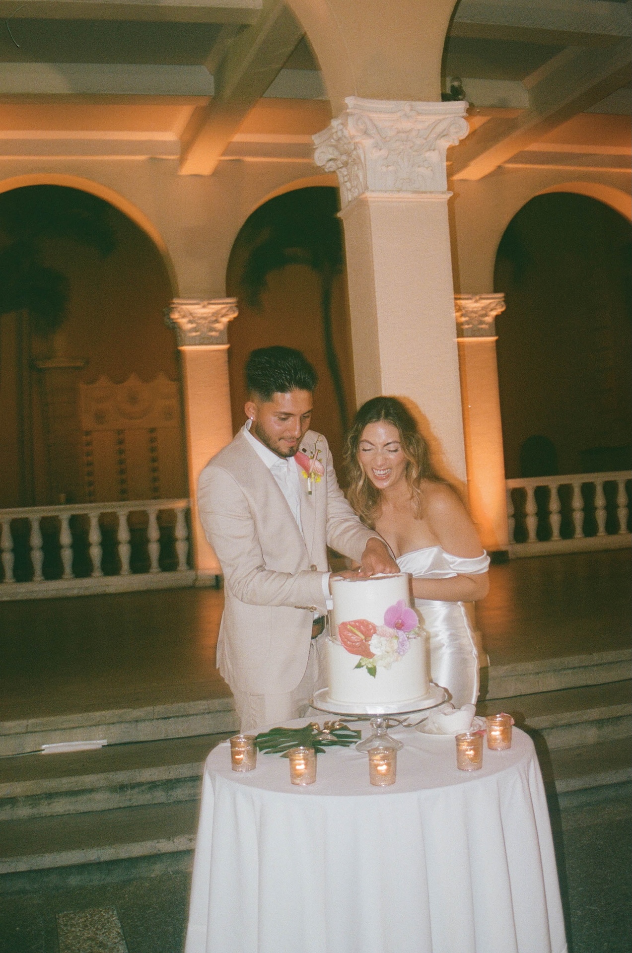 Film photo of the bride and groom laughing while cutting their first slice of wedding cake at their destination wedding in Hawaii