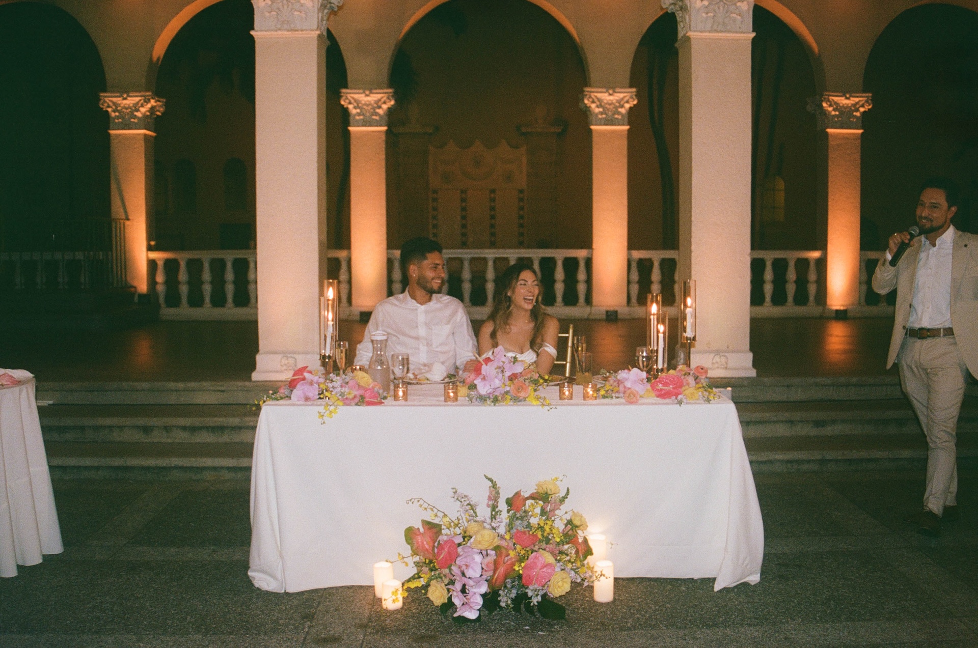 Film photo of the bride and groom laughing during speeches at their sweetheart's table during the reception at their destination wedding in Hawaii.