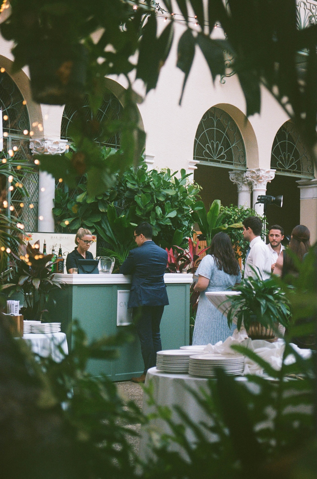 Film photo of guests waiting in line during cocktail hour for a drink surrounded by lush greenery.