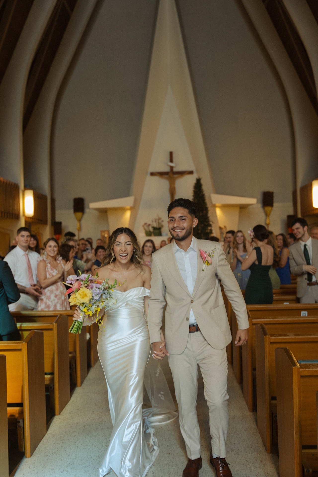 Newlyweds laughing and walking together down the church aisle after their ceremony – destination wedding in Hawaii vibes.

