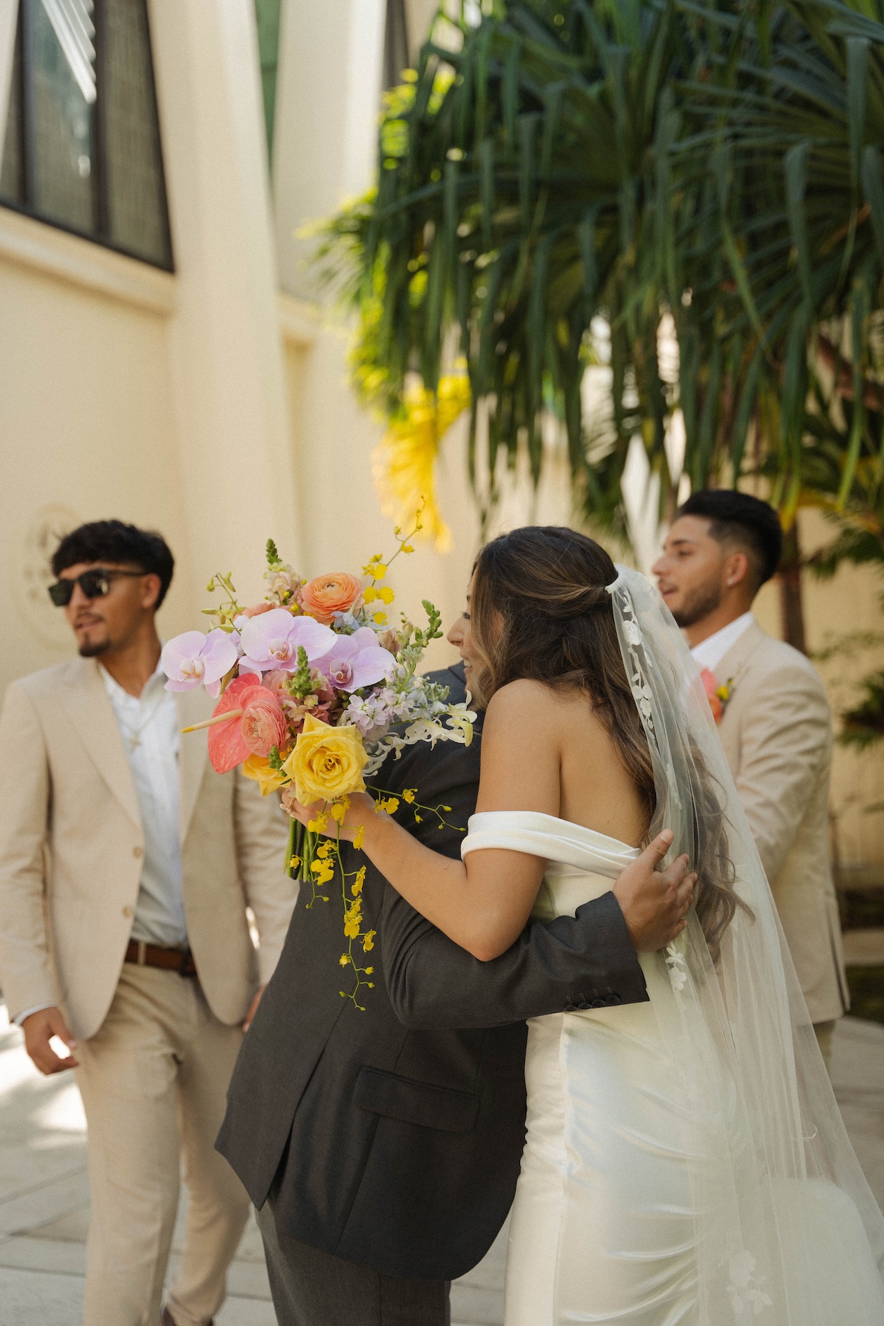 Bride hugging a guest while holding a colorful bouquet.

