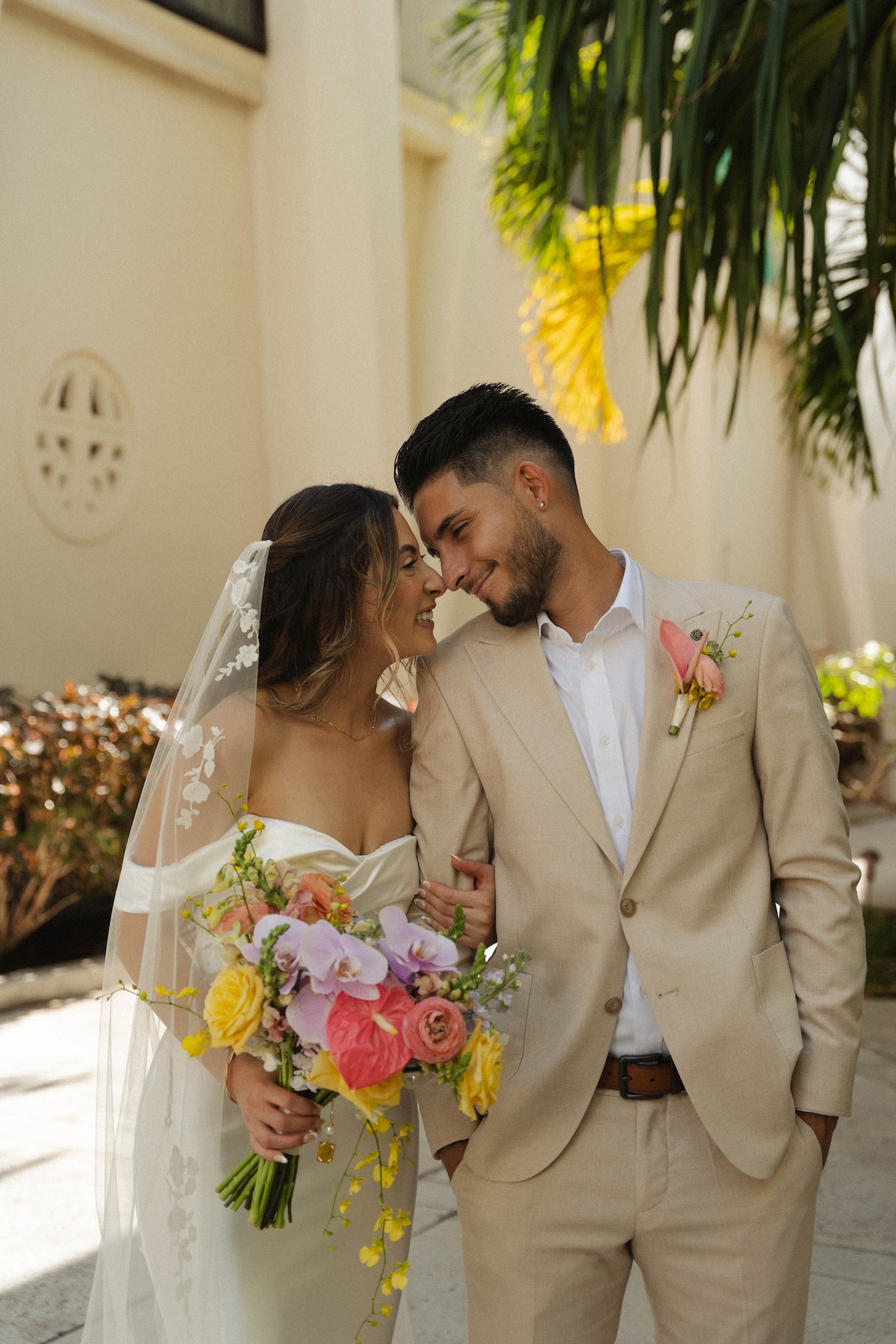 Bride and groom sharing an intimate forehead-to-forehead moment under the palm trees during their destination wedding in Hawaii.

