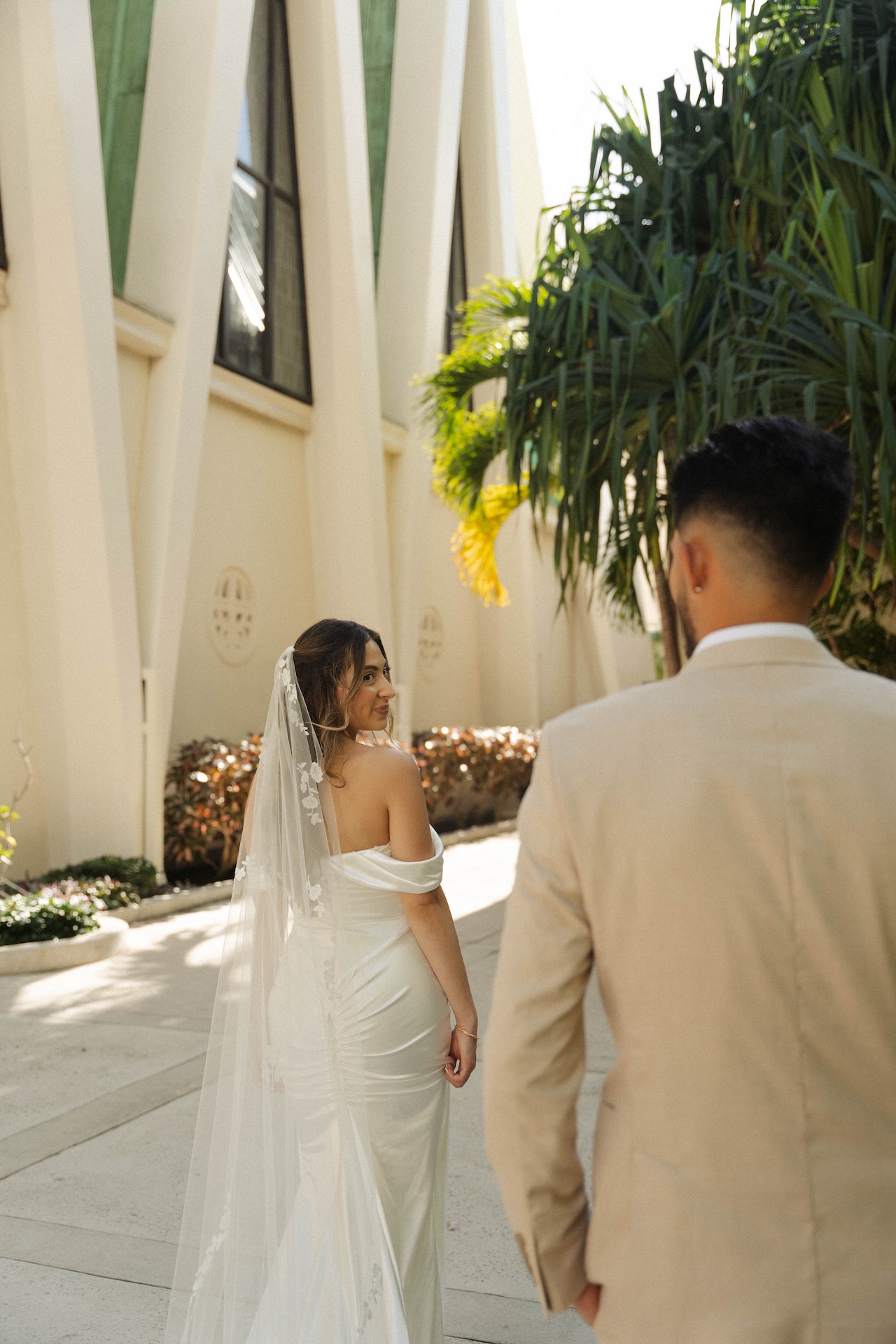 Groom walking toward the bride as she looks back with a smile — destination wedding in Hawaii moment.

