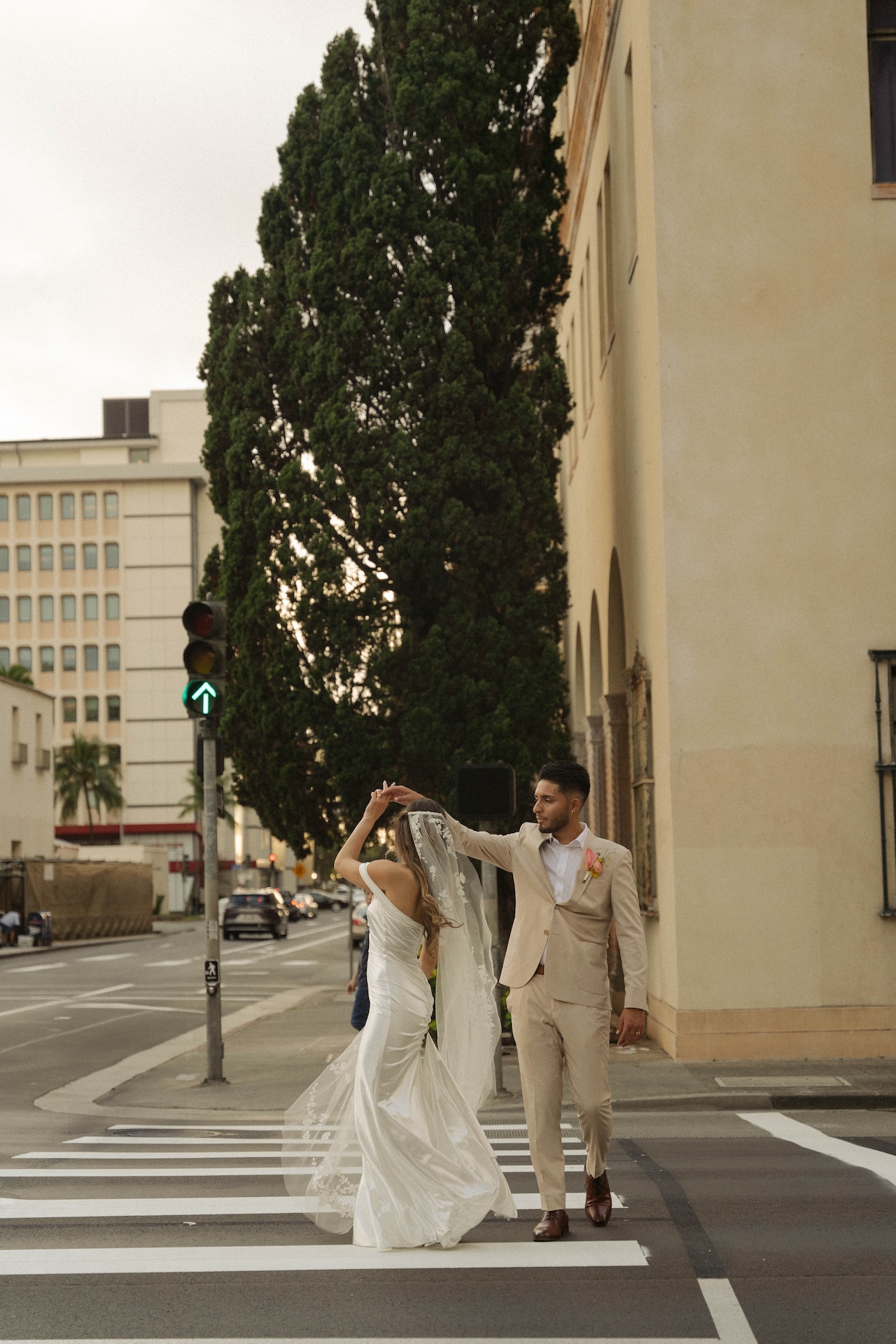 Groom twirling the bride in the street during golden hour — destination wedding in Hawaii vibes.

