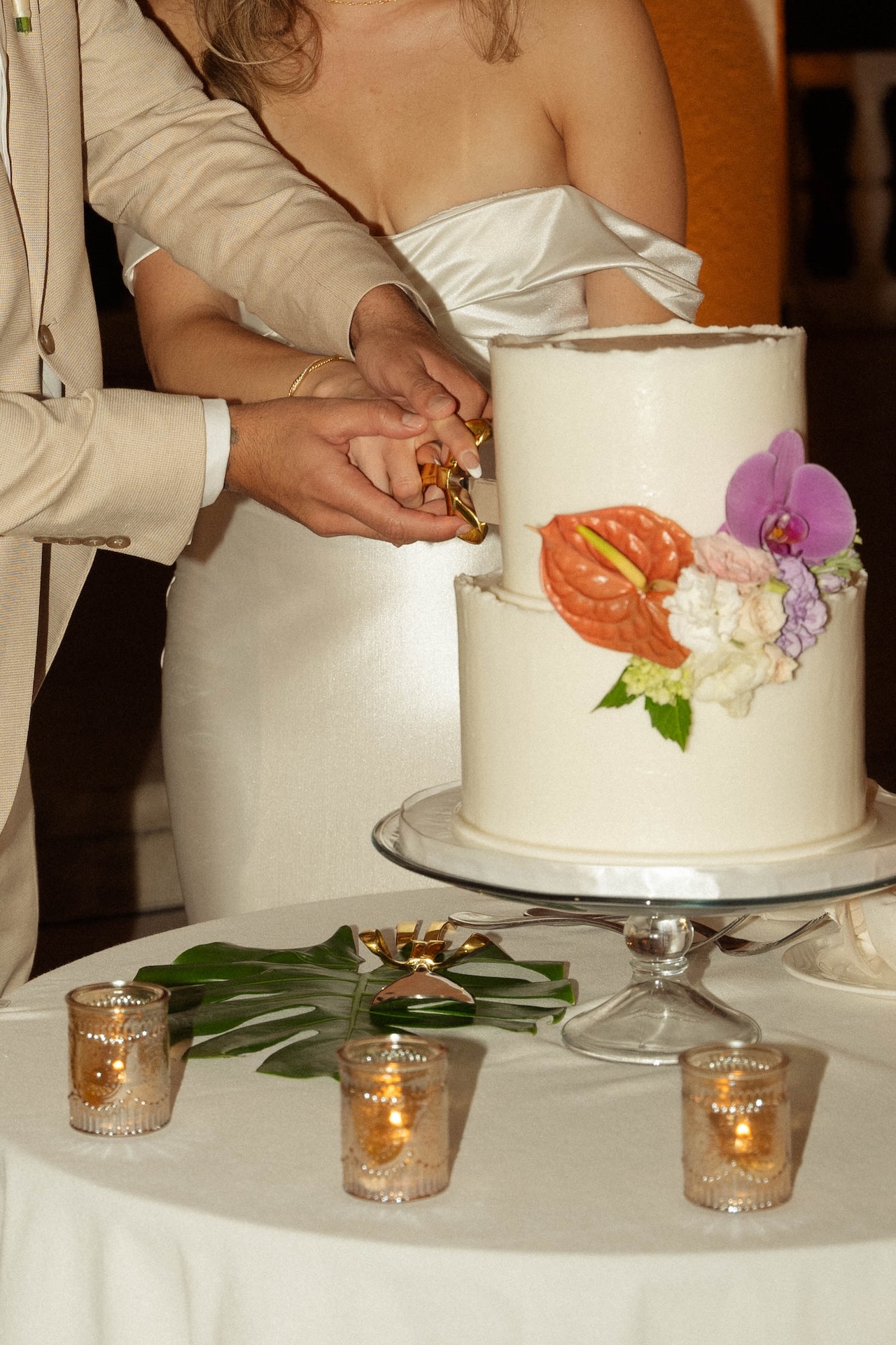 Close up of the bride and groom cutting their first slice of cake for their destination wedding in Hawaii.