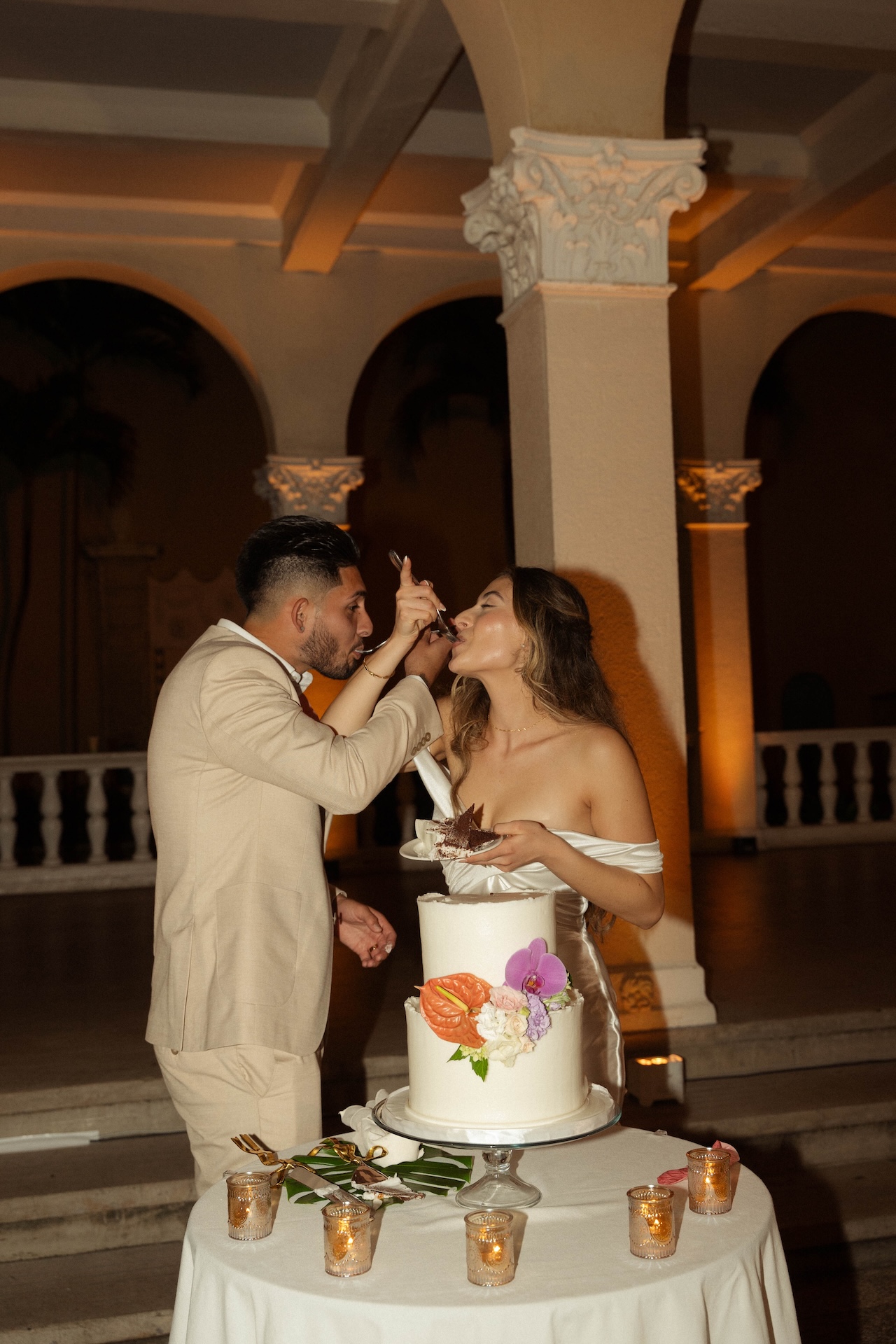 Bride and groom giving each other a bite of their wedding cake while smiling at their destination wedding in Hawaii