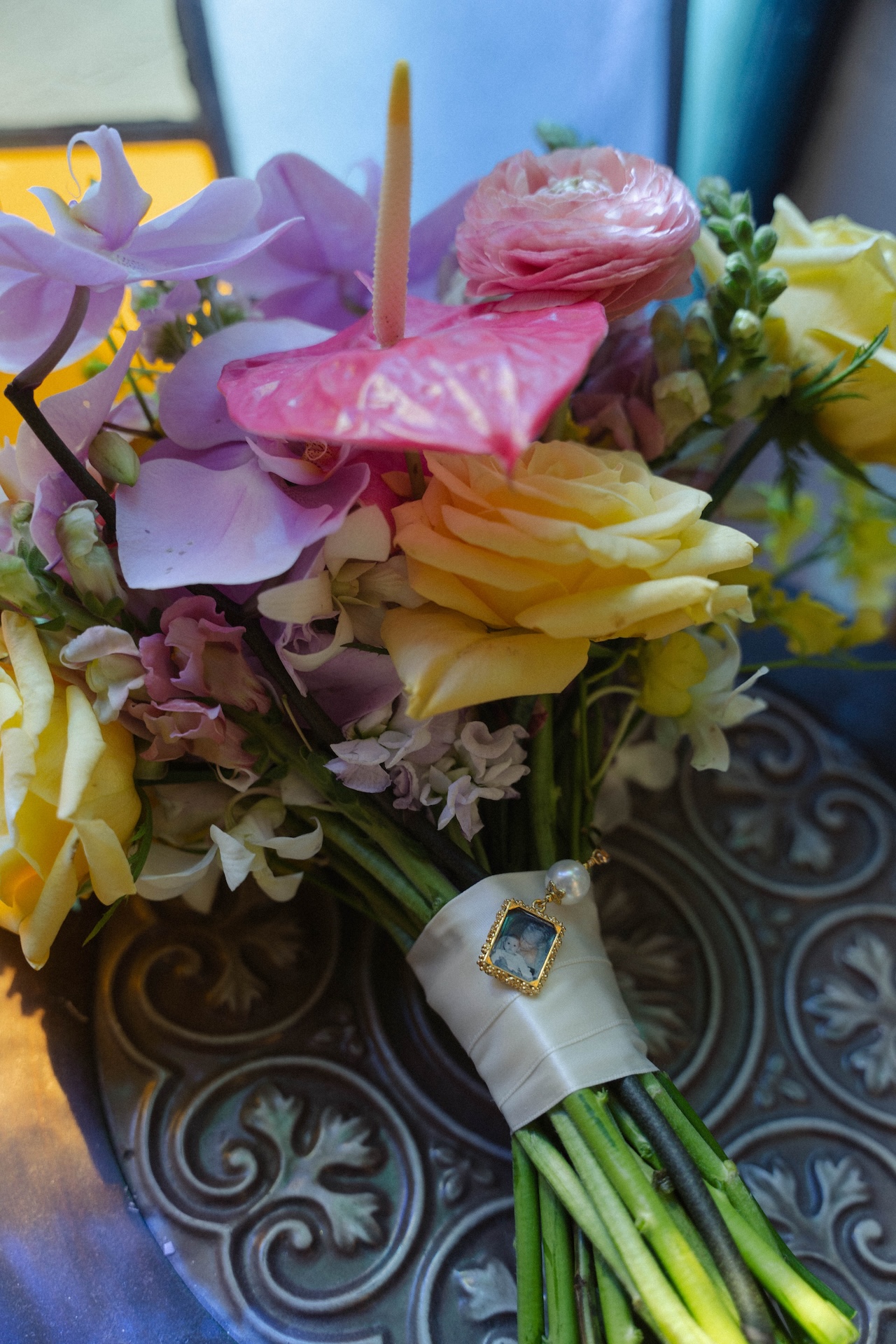 Bridal bouquet with yellow roses, pink ranunculus, and a small photo charm – perfect for a destination wedding in Hawaii.

