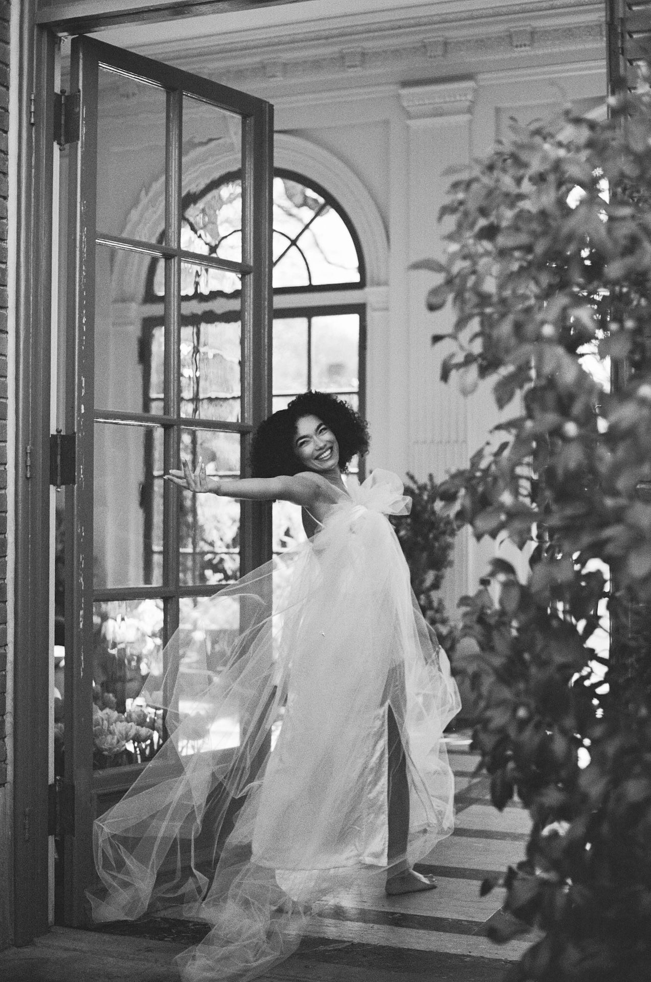 A joyful bride twirling in a flowing veil and gown inside a sunlit room at one of the most romantic wedding estate venues.

