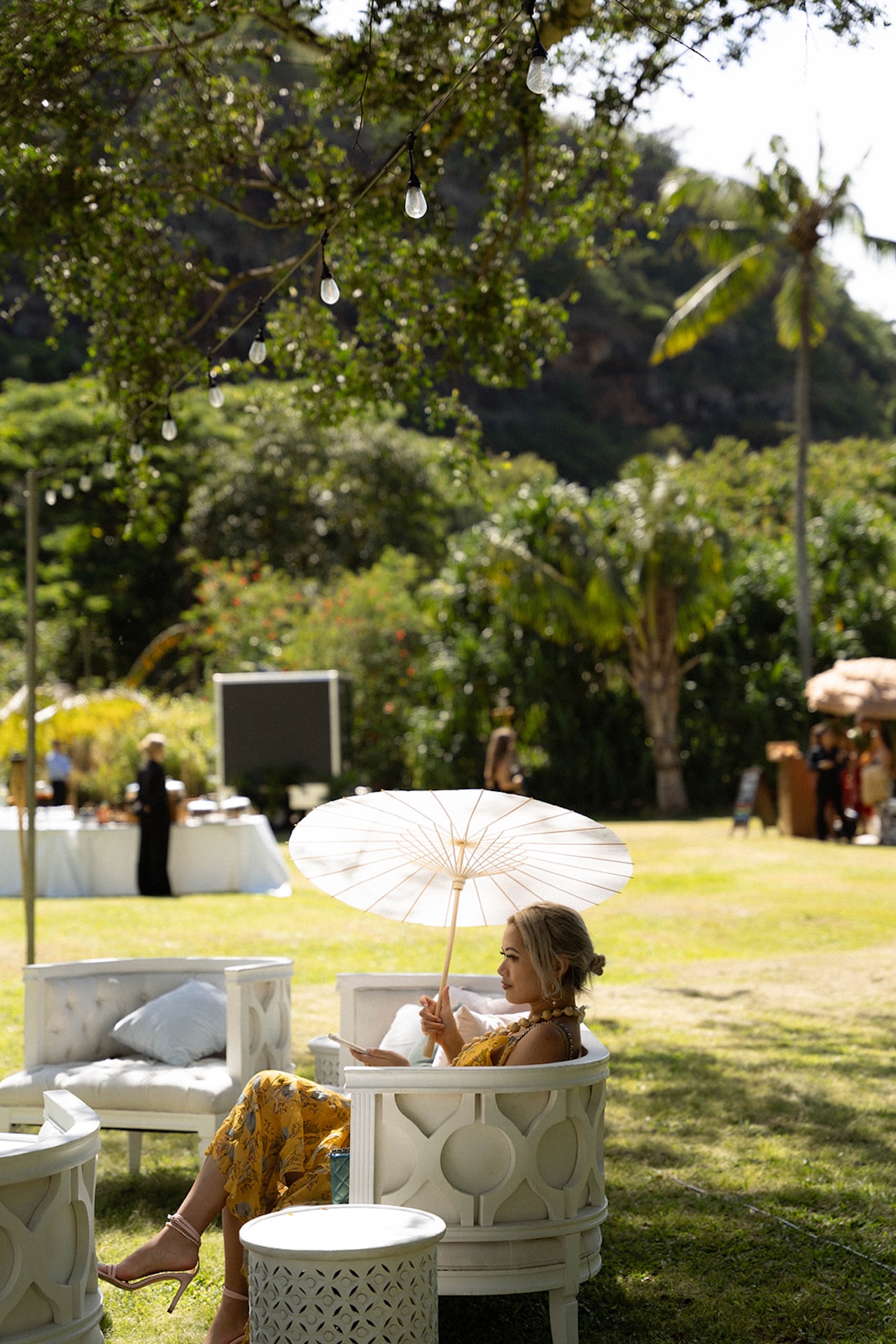 Guest lounging in a white chair under a paper parasol, soaking in the tropical scenery during cocktail hour