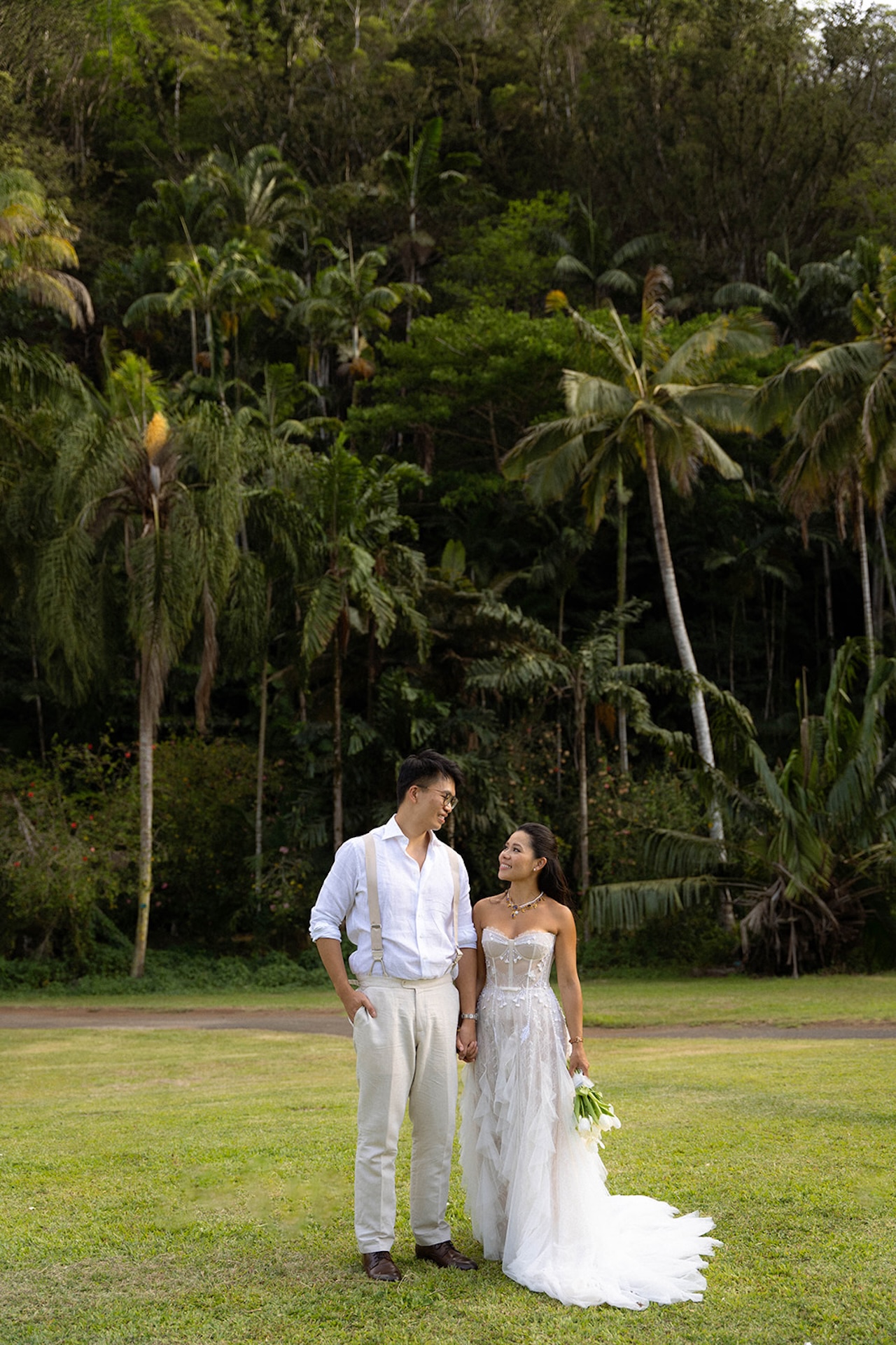 Bride and groom walking across the grass, her gown trailing behind her as they share a quiet post-ceremony moment