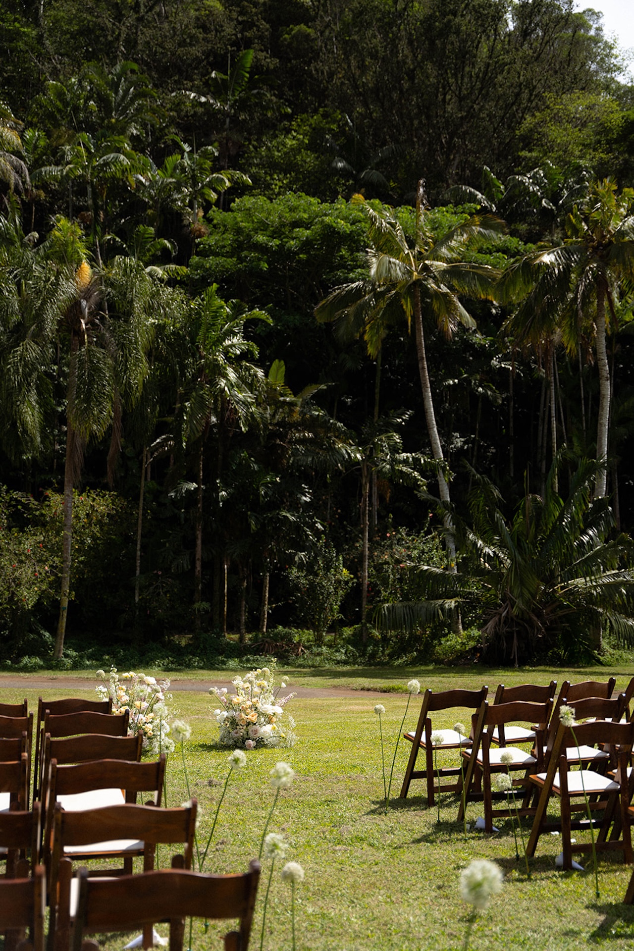 A closer look at floral aisle arrangements in an open-air ceremony space, framed by palm trees and forest greenery – a dream setting for intimate wedding venues in Hawaii