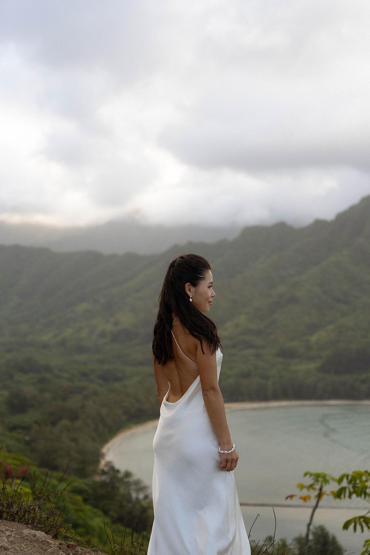 Bride standing on a cliffside, looking out at the ocean with wind in her hair — a perfect scene for couples exploring intimate wedding venues with dramatic views