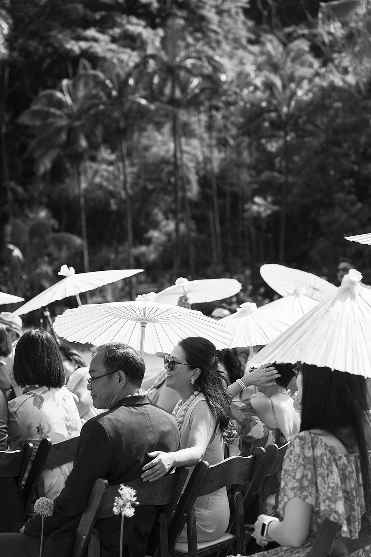Guests seated under parasols, watching the ceremony unfold in a lush, shaded area — the kind of relaxed setup you’ll find at intimate wedding venues in Hawaii