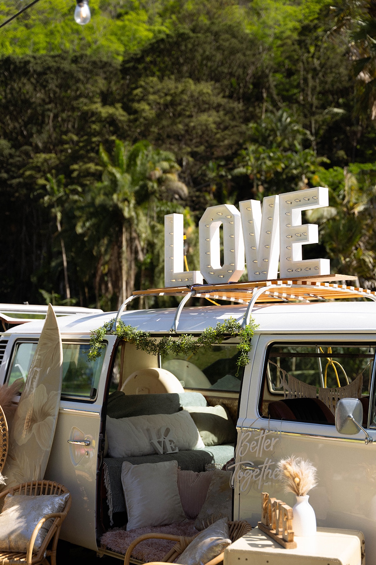 Retro white van decorated with pillows, surfboards, and a “LOVE” marquee sign — a fun photo moment often found at intimate wedding venues that blend vintage charm with natural beauty