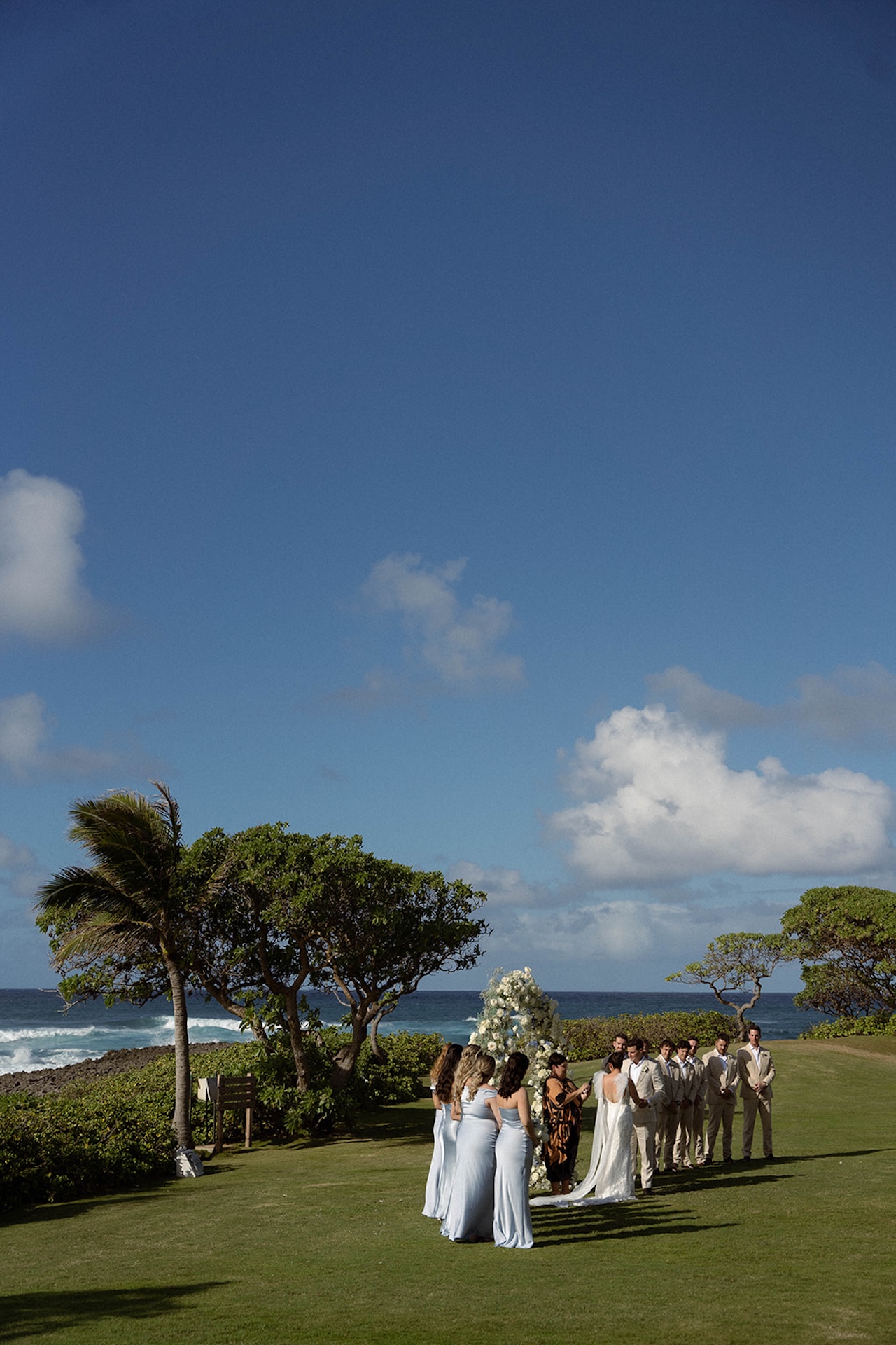 Wide view of the ceremony setup on the lawn, the bridal party standing by the arch as waves crash in the distance—an unforgettable moment in their wedding weekend itinerary.