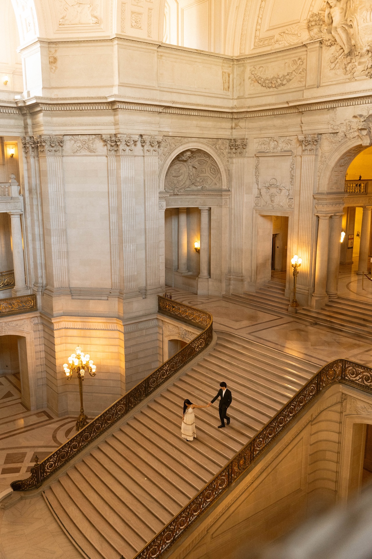 A far away shot of the bride and groom runnind down the grand staircase at the San Francisco City Hall