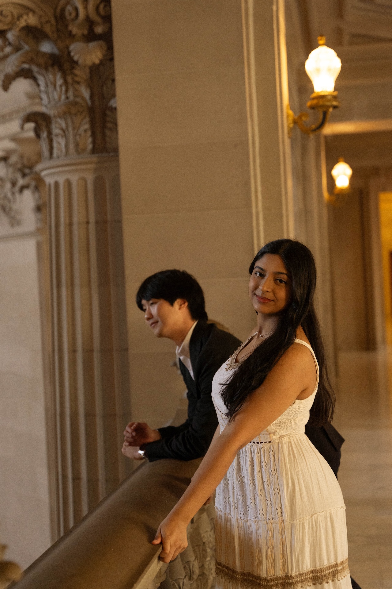 The bride and groom leaning over the stone railing at the San Francisco City Hall for their San Francisco City Hall wedding.