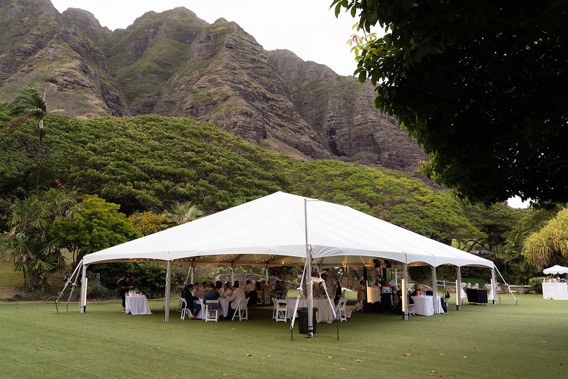 A stunning tented reception setup nestled below Oahu’s iconic mountains—an ideal setting for couples focused on Hawaii wedding planning.