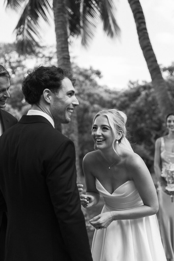 Bride laughs while holding the ring during the ceremony, sharing a candid and heartfelt moment with the groom.