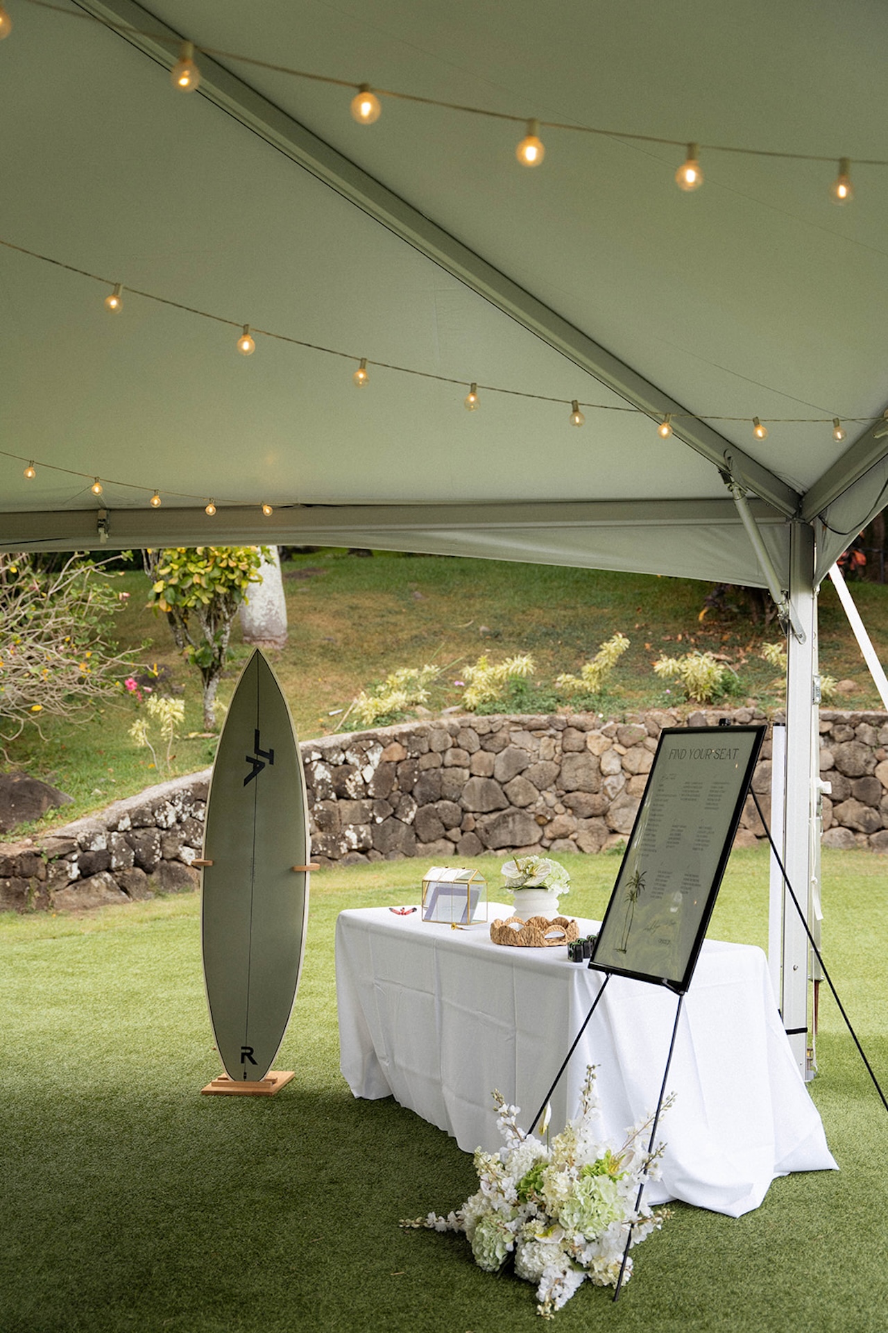 Hawaii wedding planning table featuring a surfboard guestbook, seating chart, and tropical floral arrangements.