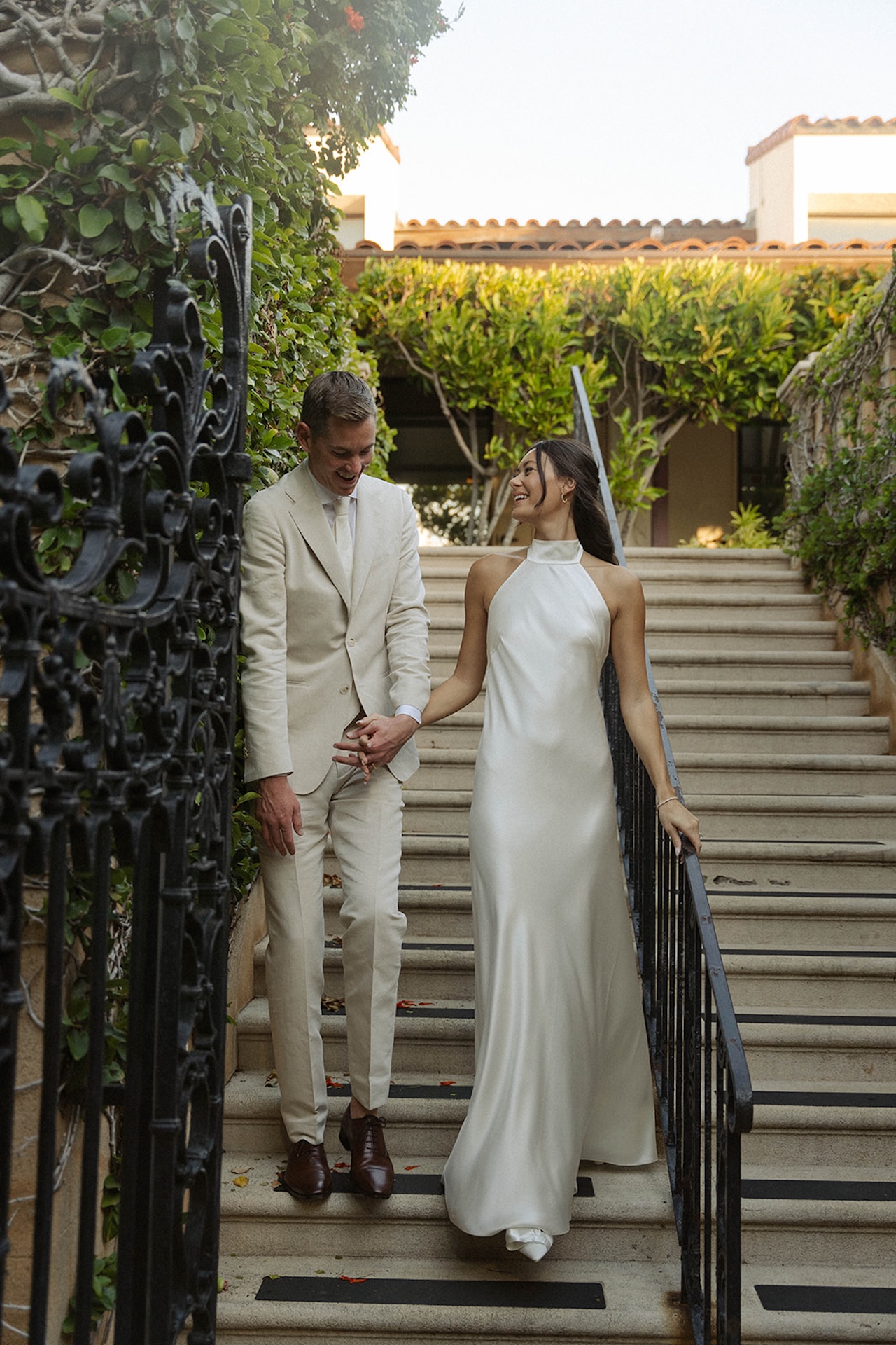 The couple walking hand in hand down stone steps, beaming with joy — a candid reflection of their intimate wedding.
