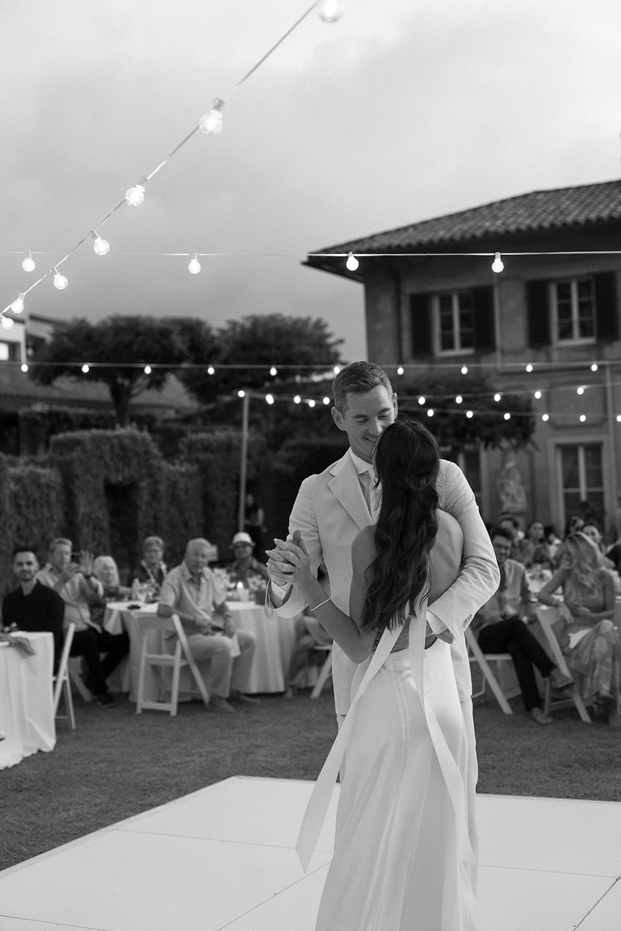 A black and white image of the couple dancing beneath the trees and string lights, perfectly framing the emotion and romance of the best destination wedding locations.