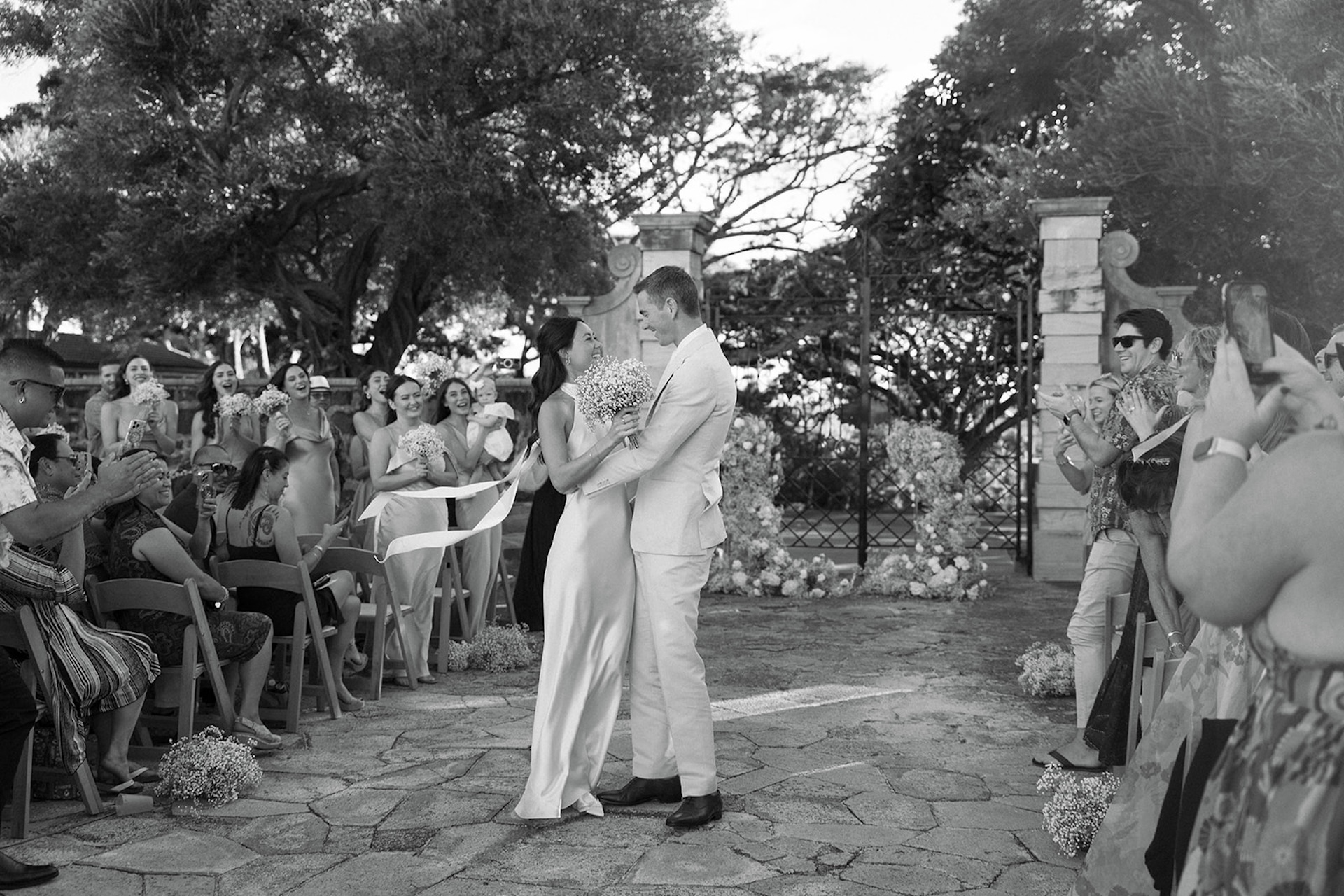 Sunlit courtyard ceremony framed by trees and stone gates, showcasing one of the best destination wedding locations for timeless celebrations.