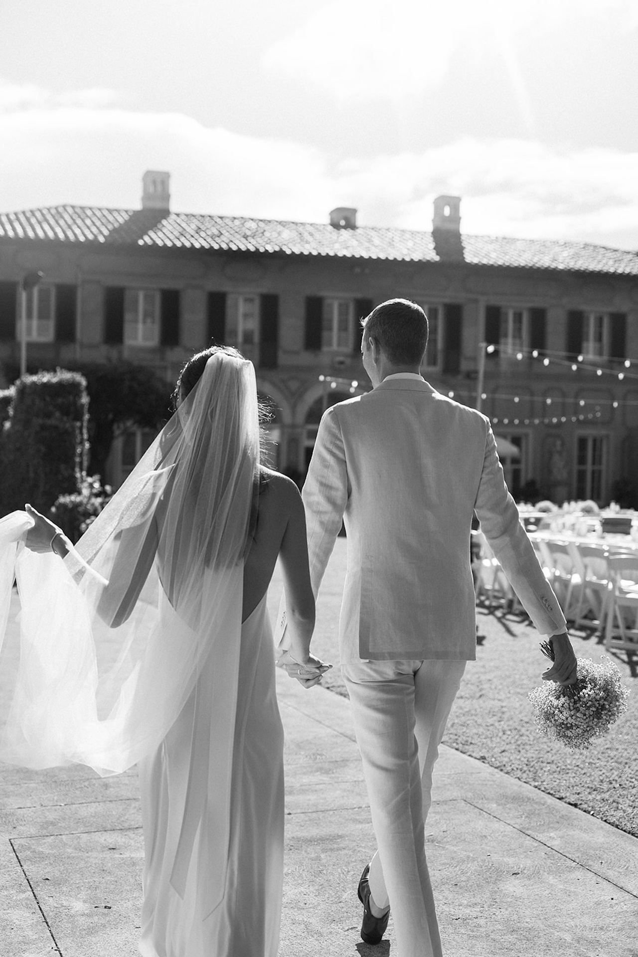 A romantic bride and groom stroll through sunlit gardens, highlighting timeless style and coastal charm found in the best destination wedding locations.