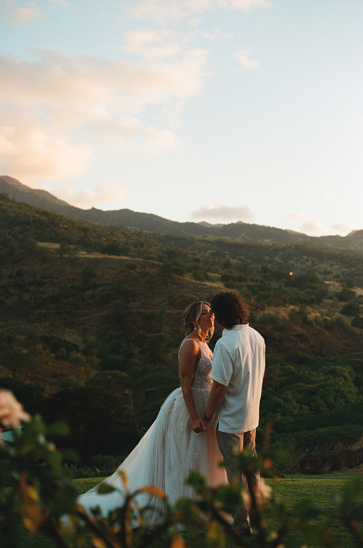 Bride and groom sharing a quiet kiss at sunset, framed by the rolling hills of Wedding Venues in Hawaii.