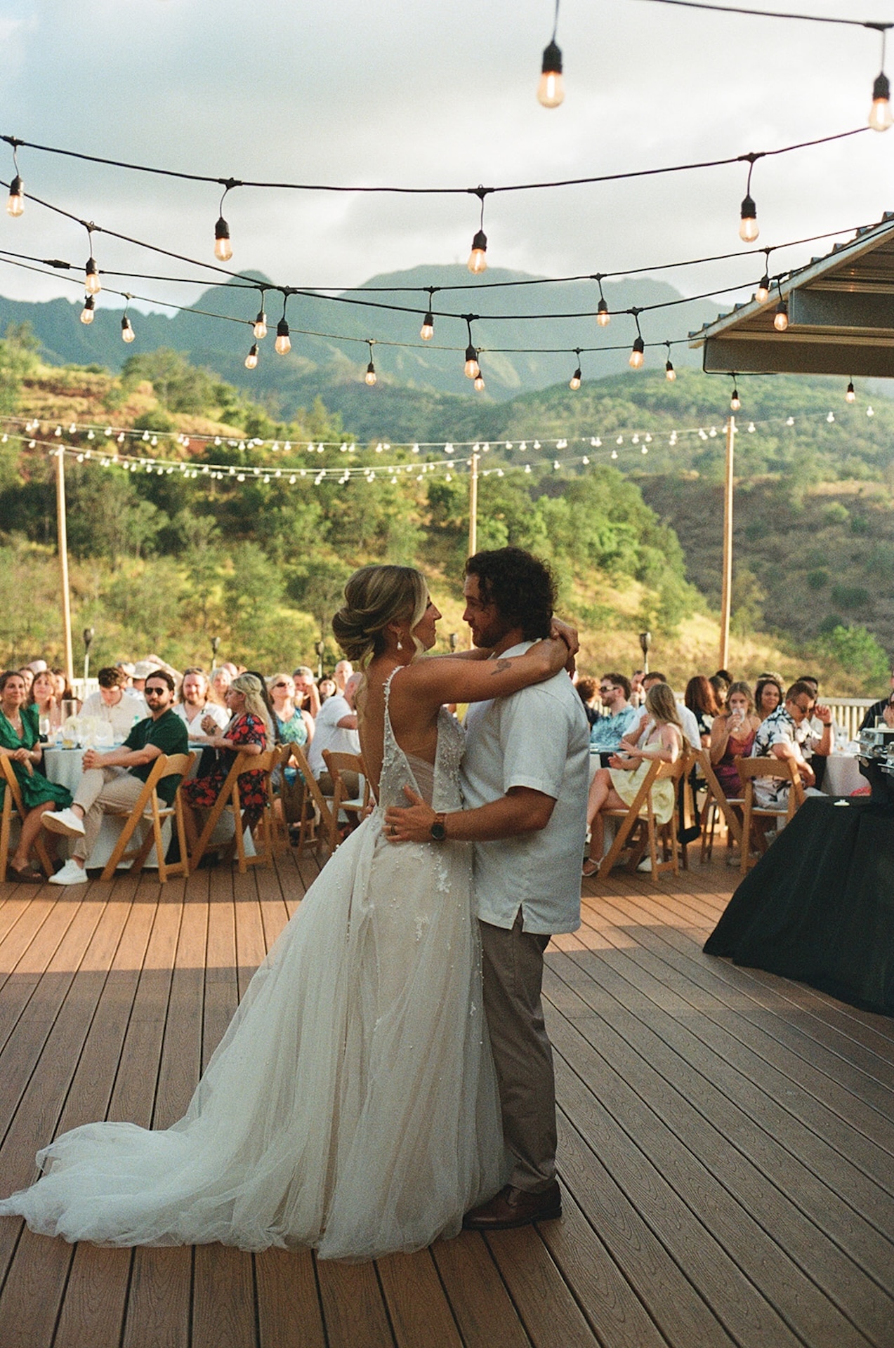 Couple laughing together while dancing outdoors with the mountains glowing in the background.