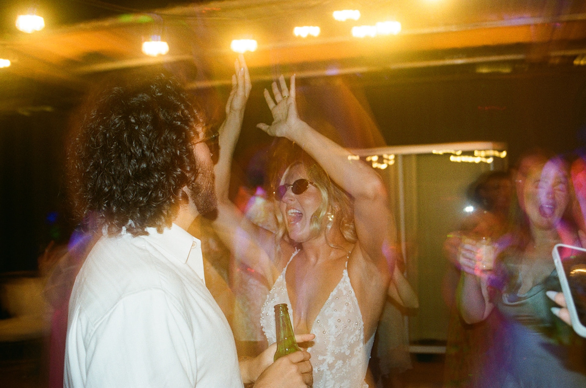 Bride and groom dancing together with sunglasses on during their wedding reception.