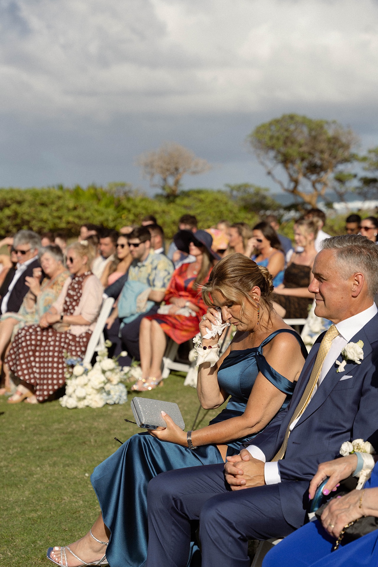 A guest in a satin gown wipes away tears during the ceremony, moved by the vows—an emotional part of the wedding weekend itinerary.