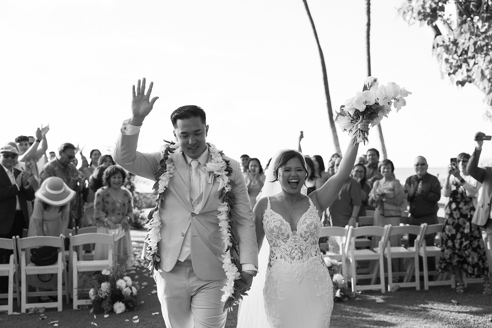 The bride and groom walking down the aisle, cheering and smiling while guests applaud, one of the best celebration moments to plan for in your Destination wedding checklist.